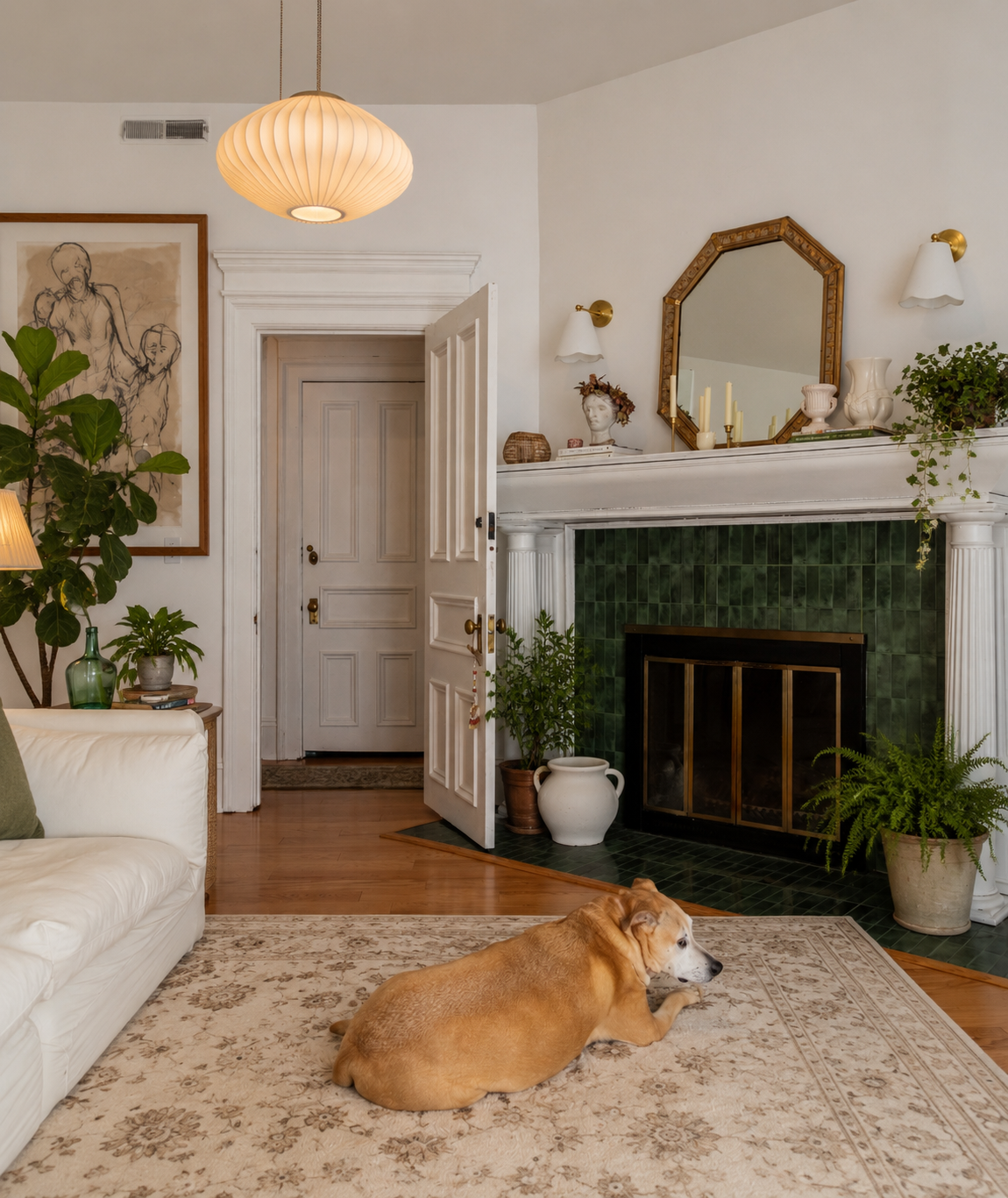 Living room by Linda McDermott of McDermott Interiors, Portland, OR. A warm, inviting space featuring a white sofa, green tile fireplace, layered greenery, curated artwork, and timeless styling with natural textures.