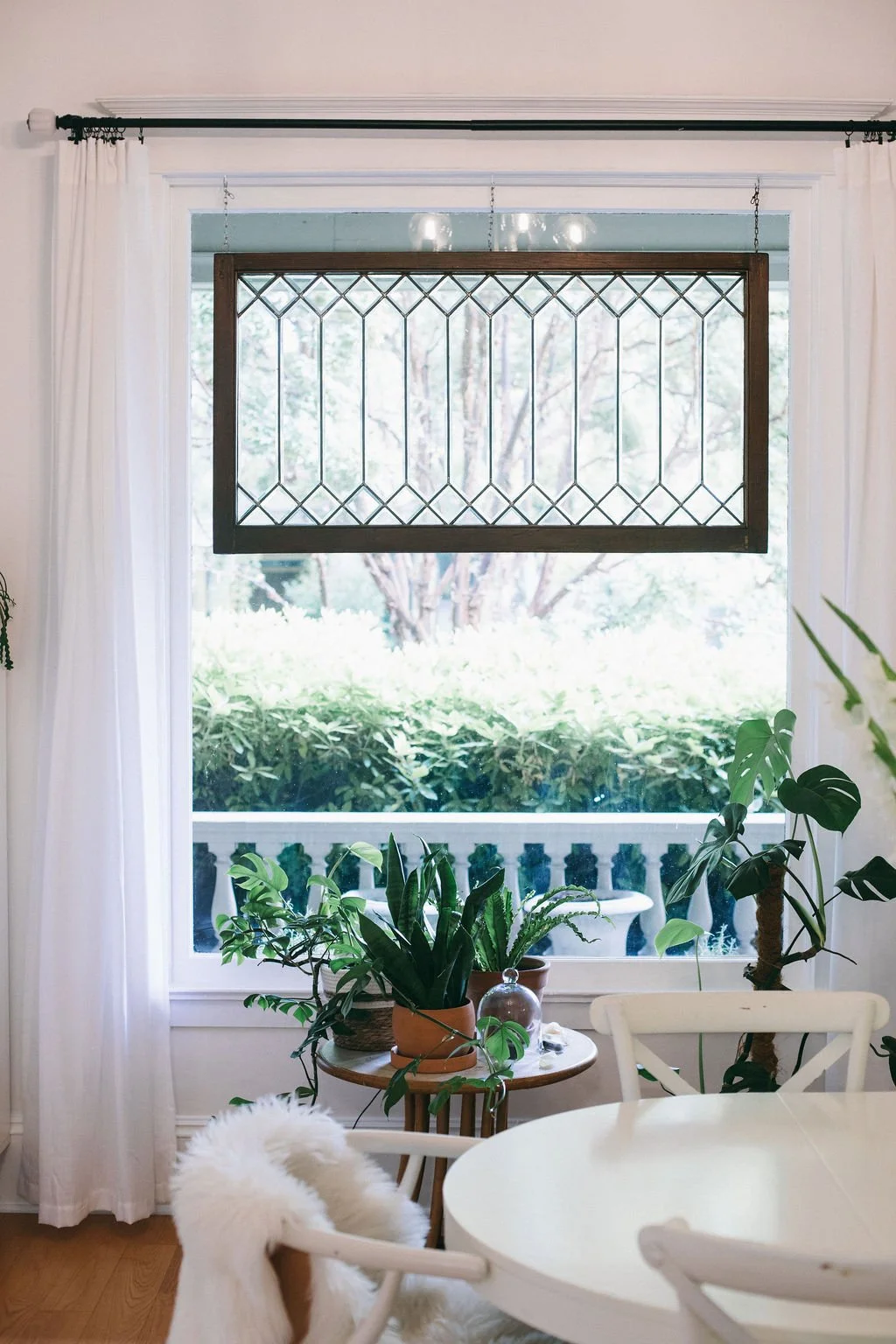 Bright dining room with a white table and chairs, large windows, white curtains, and lush greenery, showcasing the warm, natural interior design style of Linda McDermott and McDermott Interiors in Portland, Oregon, serving the Portland Metro Area.