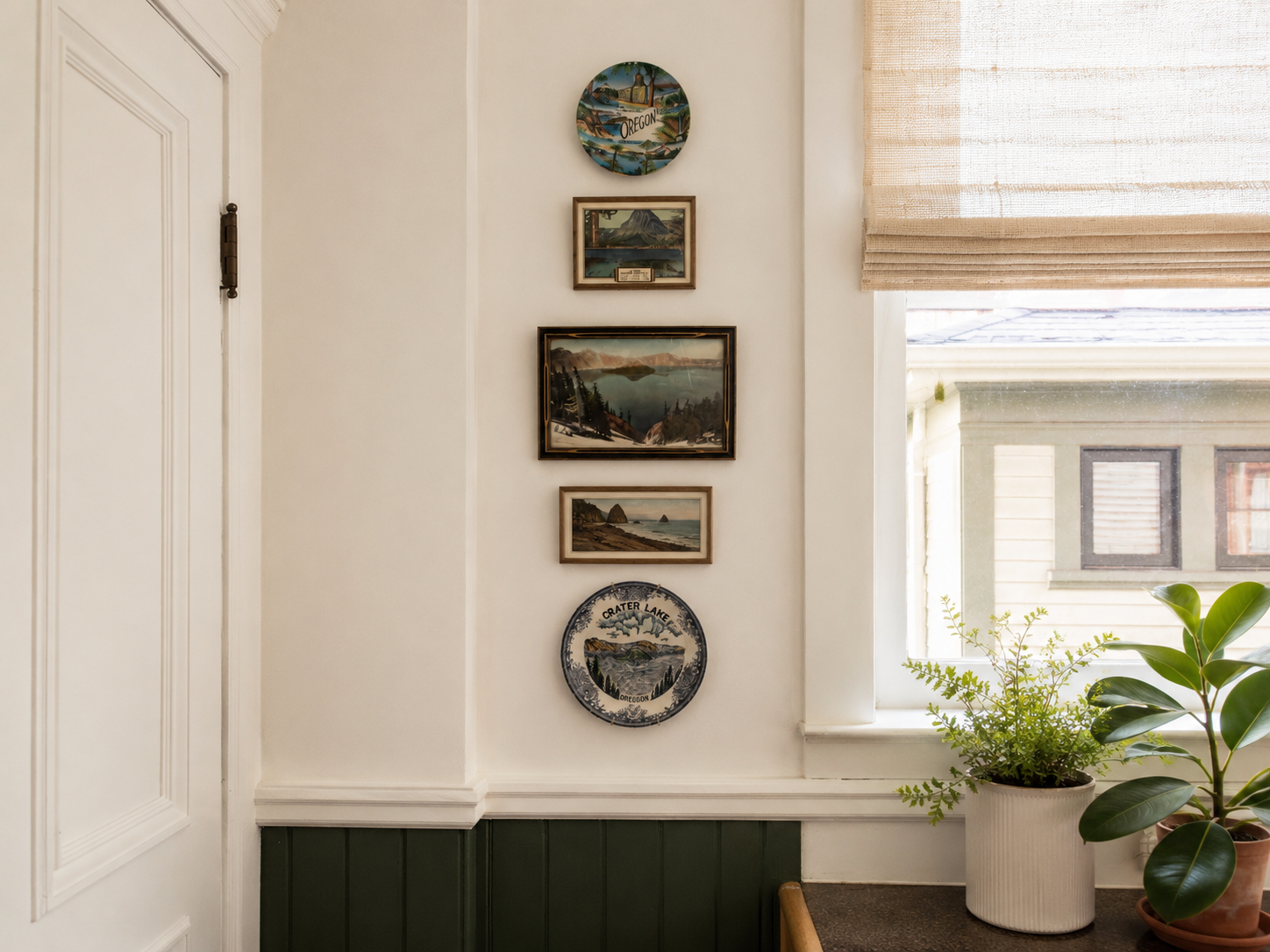 Kitchen detail by Linda McDermott of McDermott Interiors, Portland, OR. A thoughtfully styled wall featuring vintage Oregon landscape plates, lush greenery, and natural light that adds warmth and character to the space.