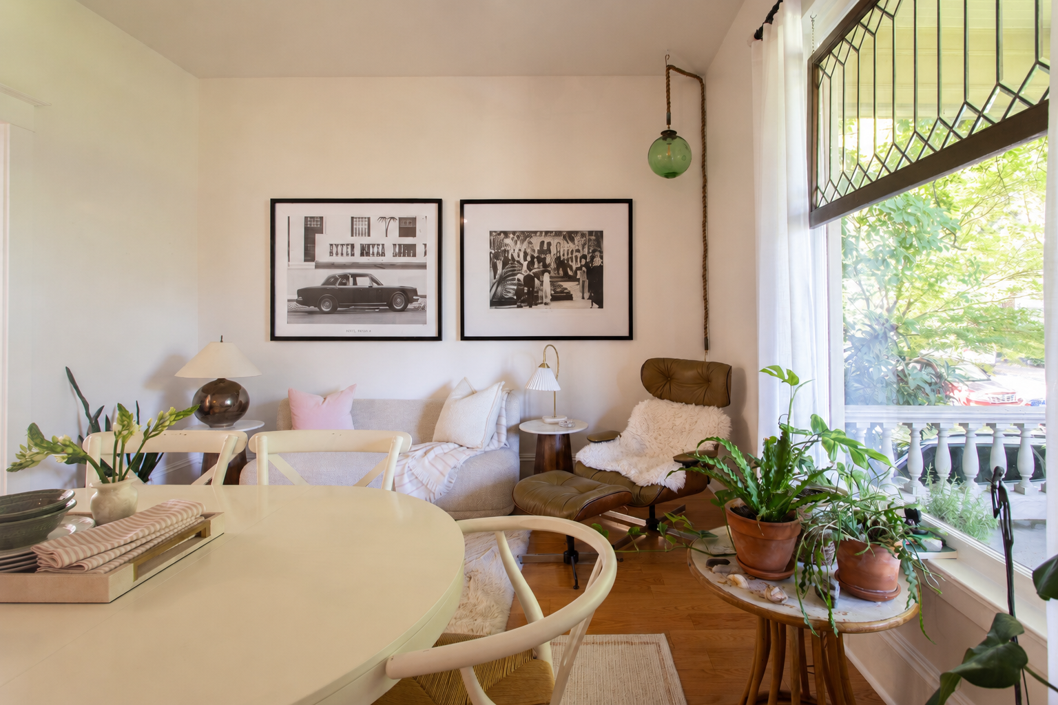 Living room by Linda McDermott of McDermott Interiors, Portland, OR. An inviting open-concept living space featuring a round dining table, layered greenery, a comfortable neutral sofa, curated artwork, and large windows that fill the home with natura
