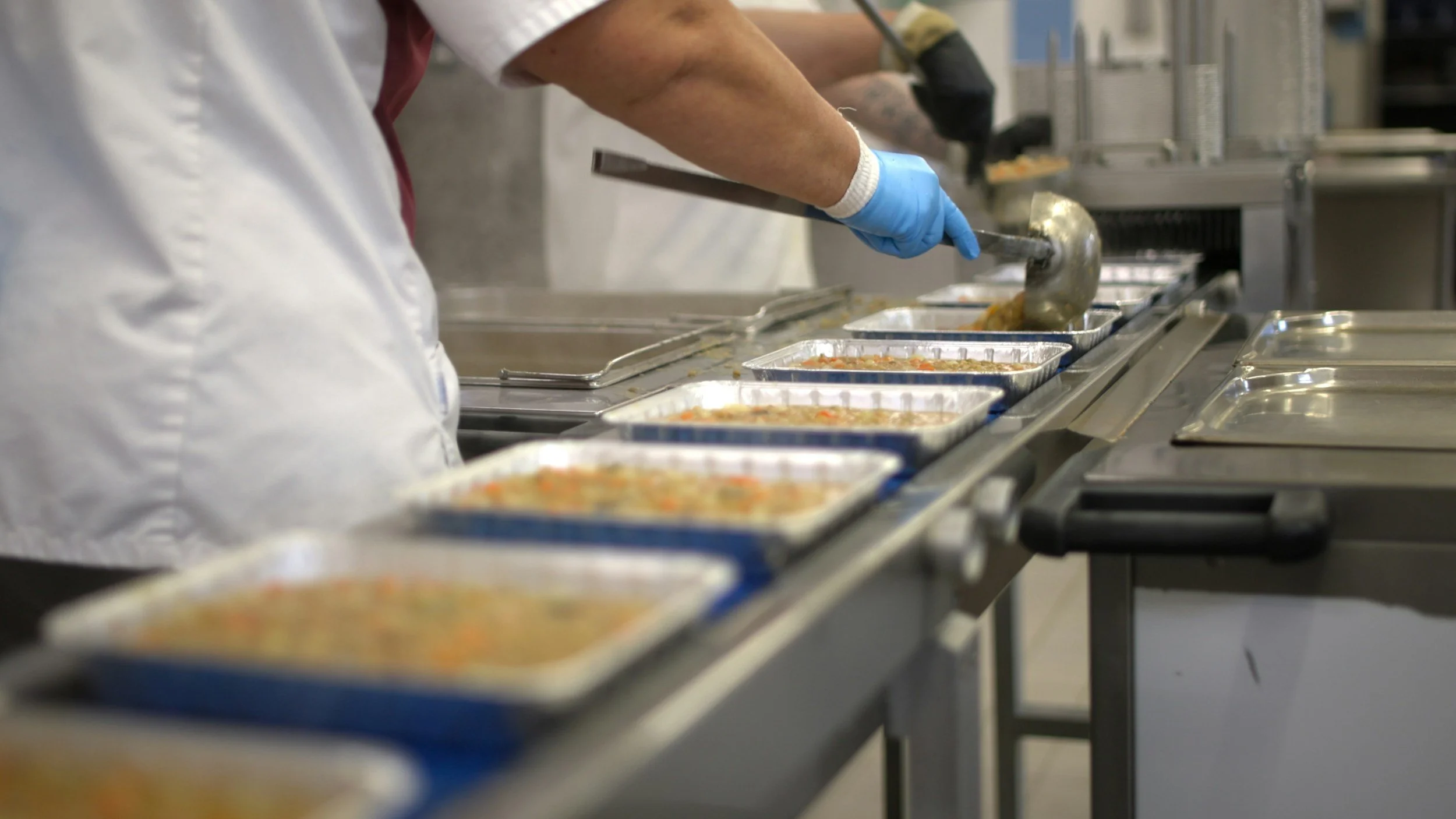 Food Services and picture of person wearing a white smock serving food from a tray a prepared food. #shelterfood, #shelterservice, #foodservicesprogram