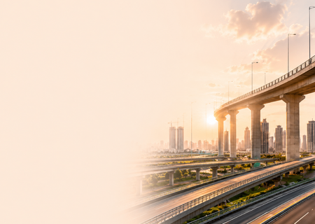 City skyline at sunset with elevated highway and bridge.