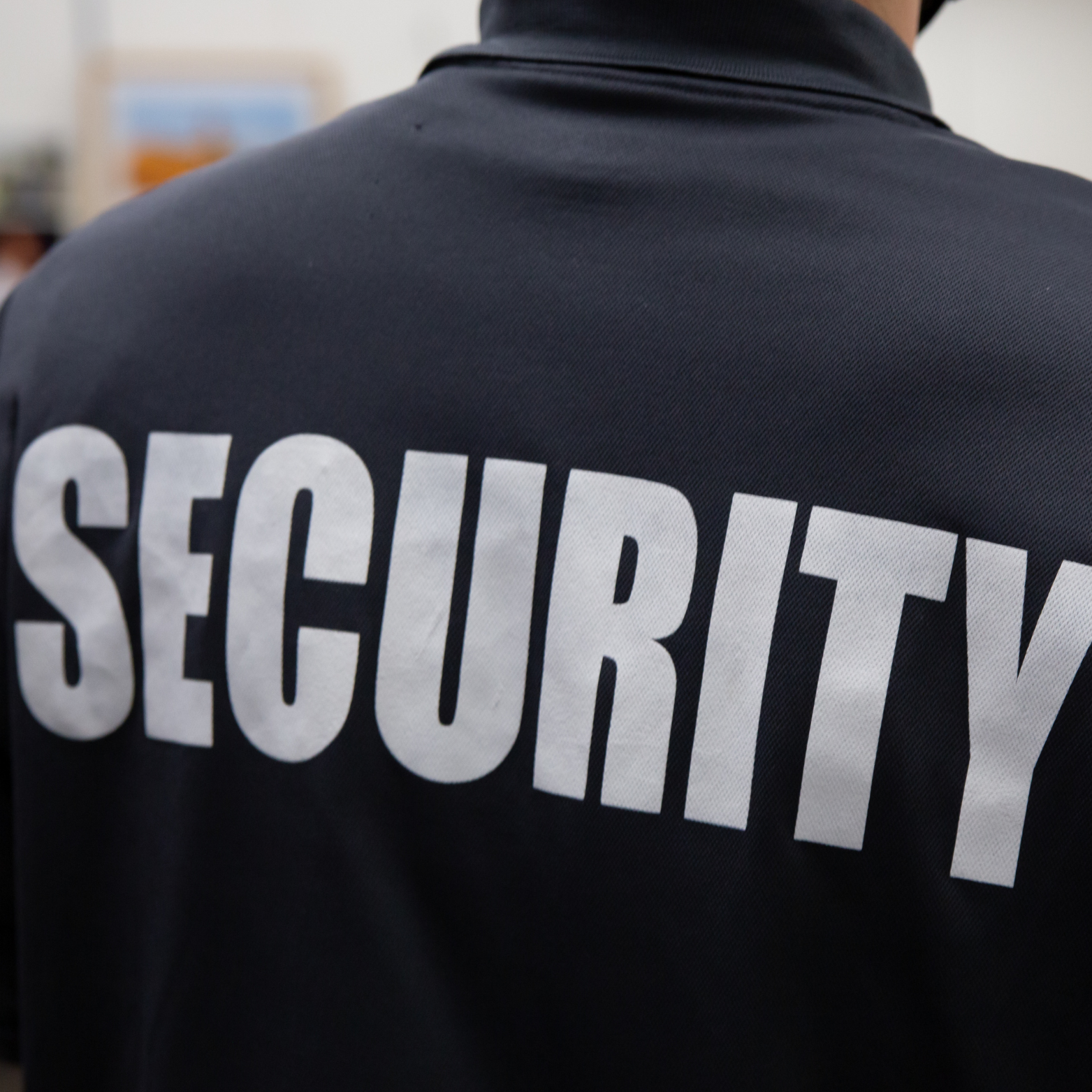 Back of a security guard's uniform with the word 'SECURITY' printed in large white letters.