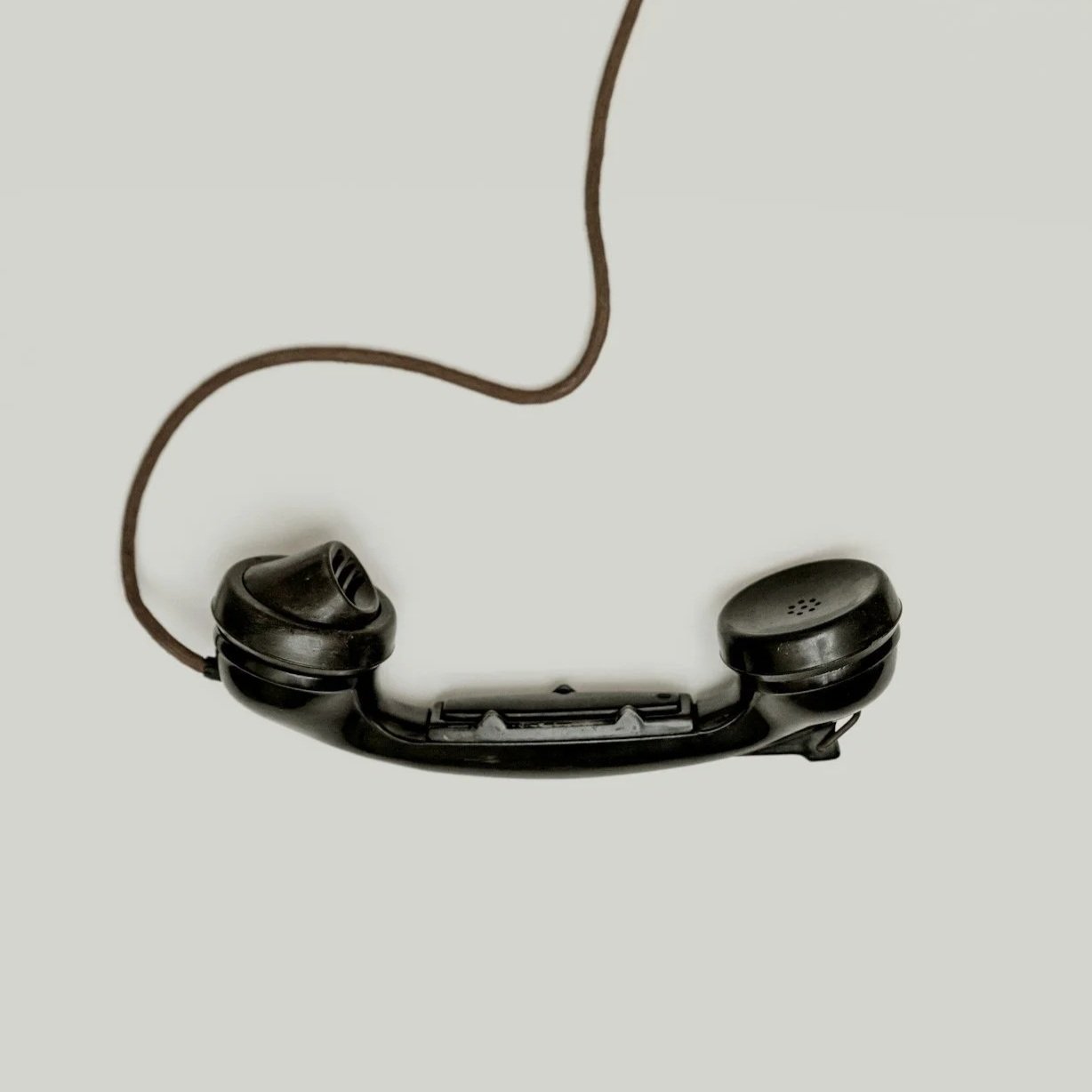 A pair of black in-ear wired headphones with a brown cord, photographed against a plain white background.