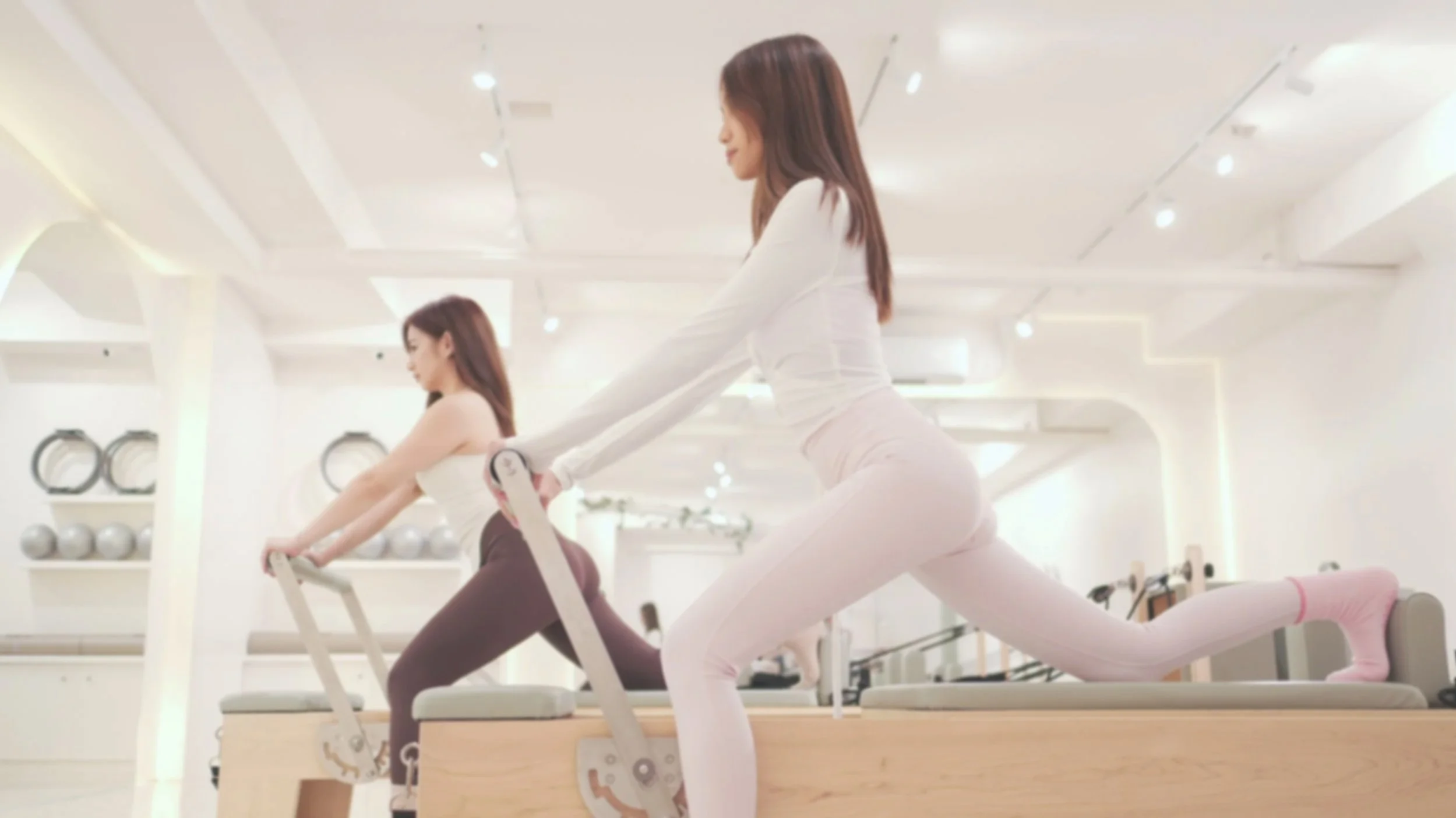 Close-up of a white wall with a modern decorative art piece consisting of three angular crescent shapes, with blurred objects in the foreground.