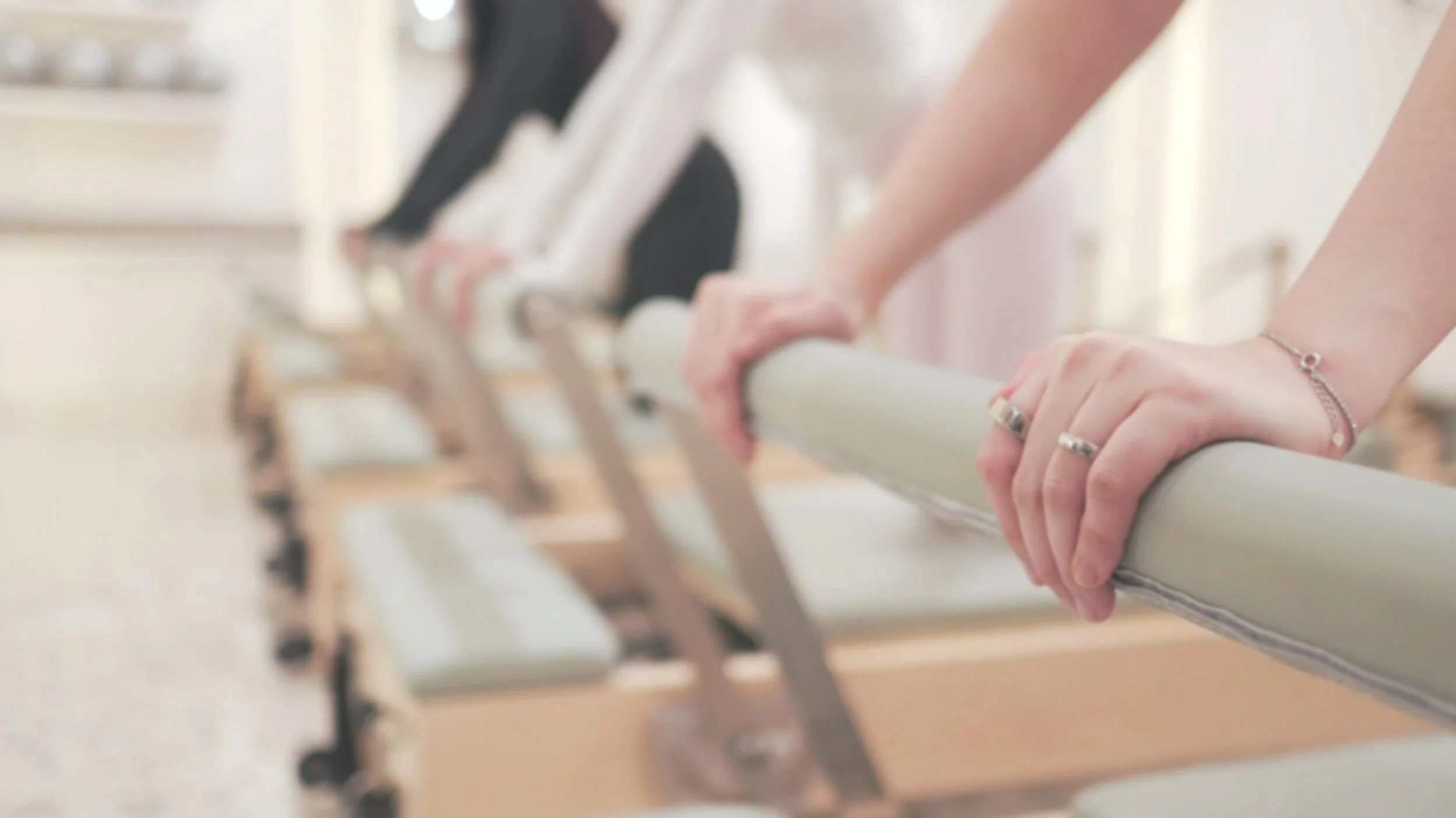 Row of adjustable, padded medical or therapy examination tables with metal arms and foot controls. Light-colored wood frames and mint green cushions.