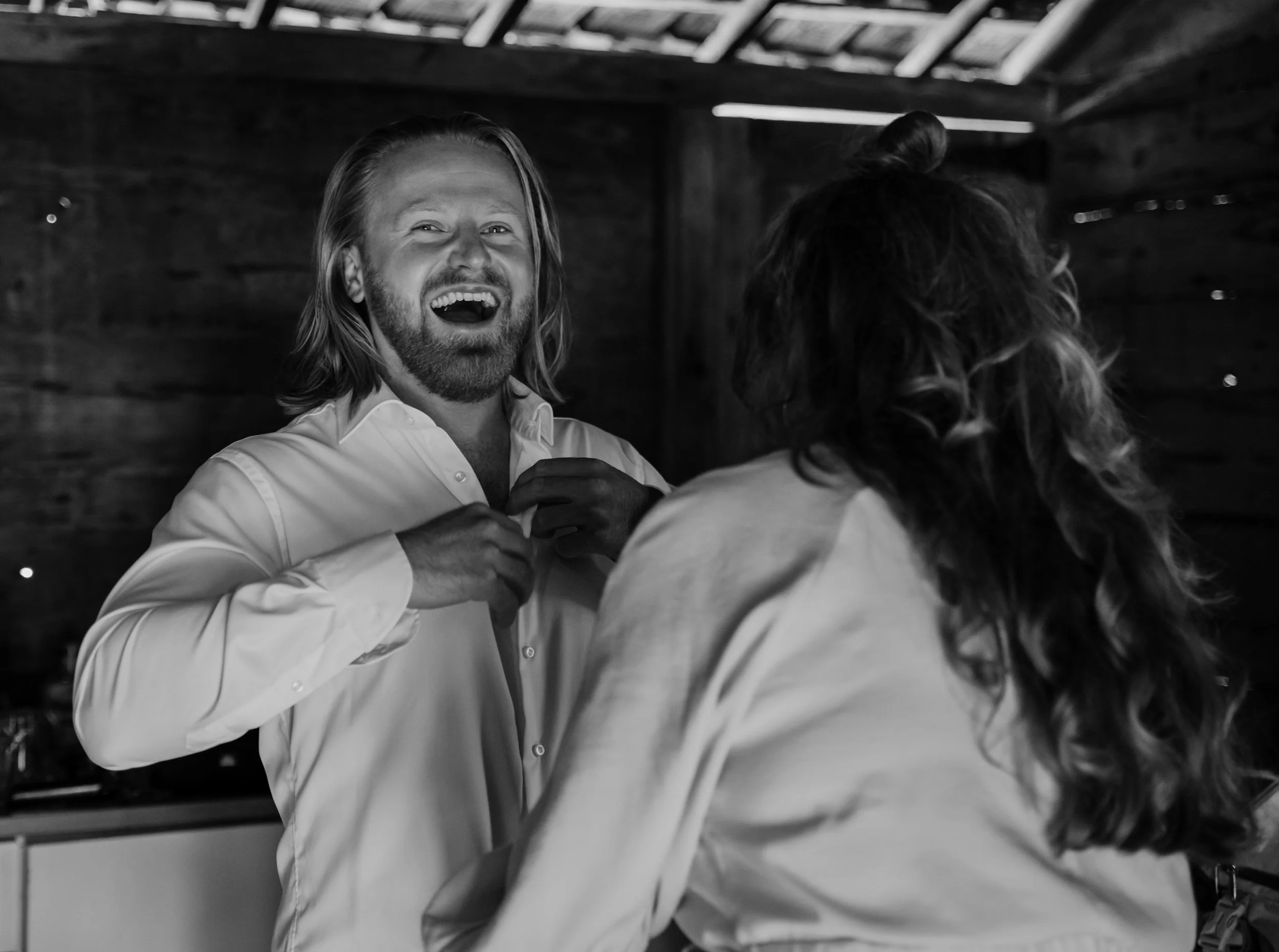 Lachende man en vrouw die elkaar vasthouden in een houten schuur.