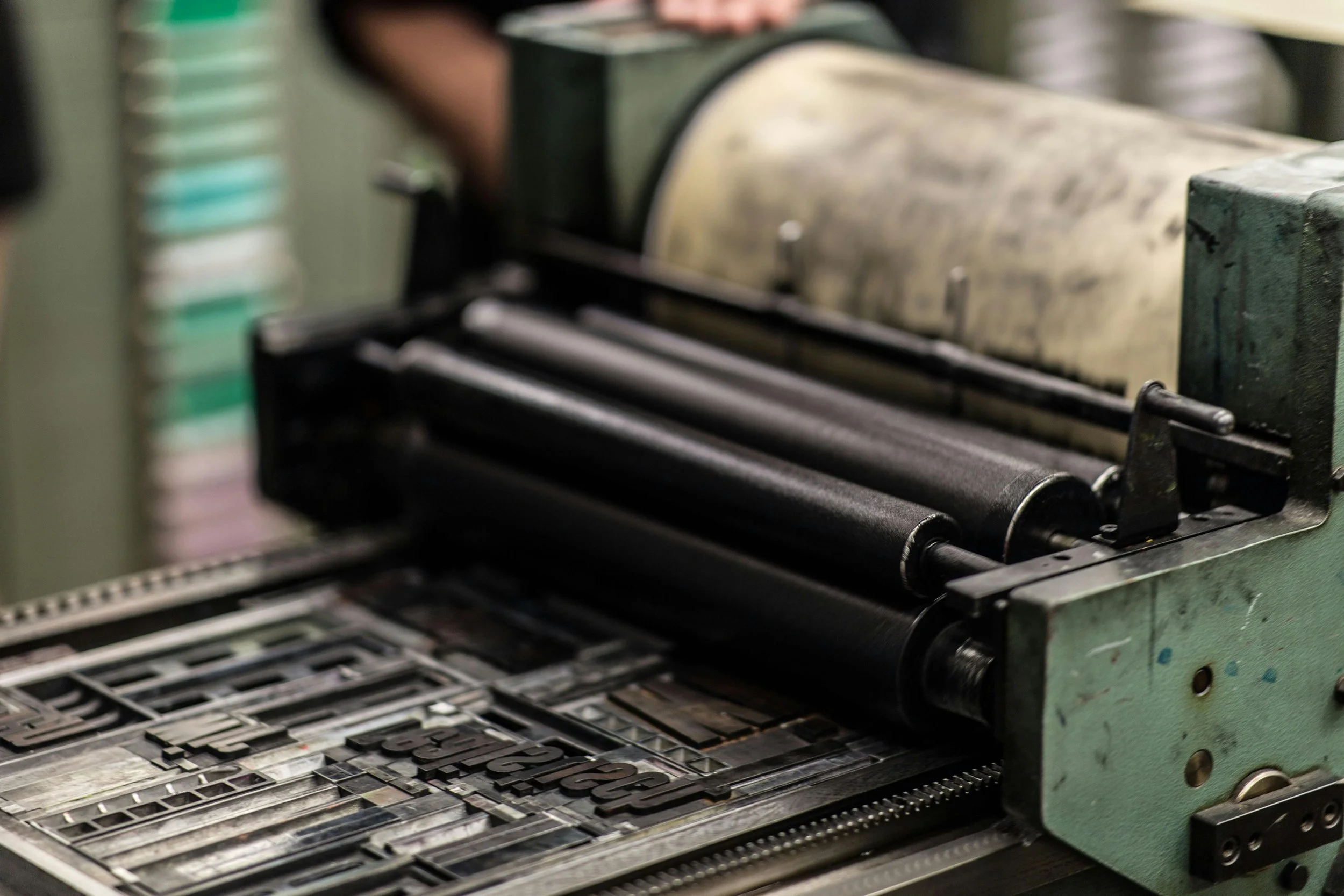 Close-up of a vintage letterpress machine used for printing, with metal type blocks arranged on the press bed.