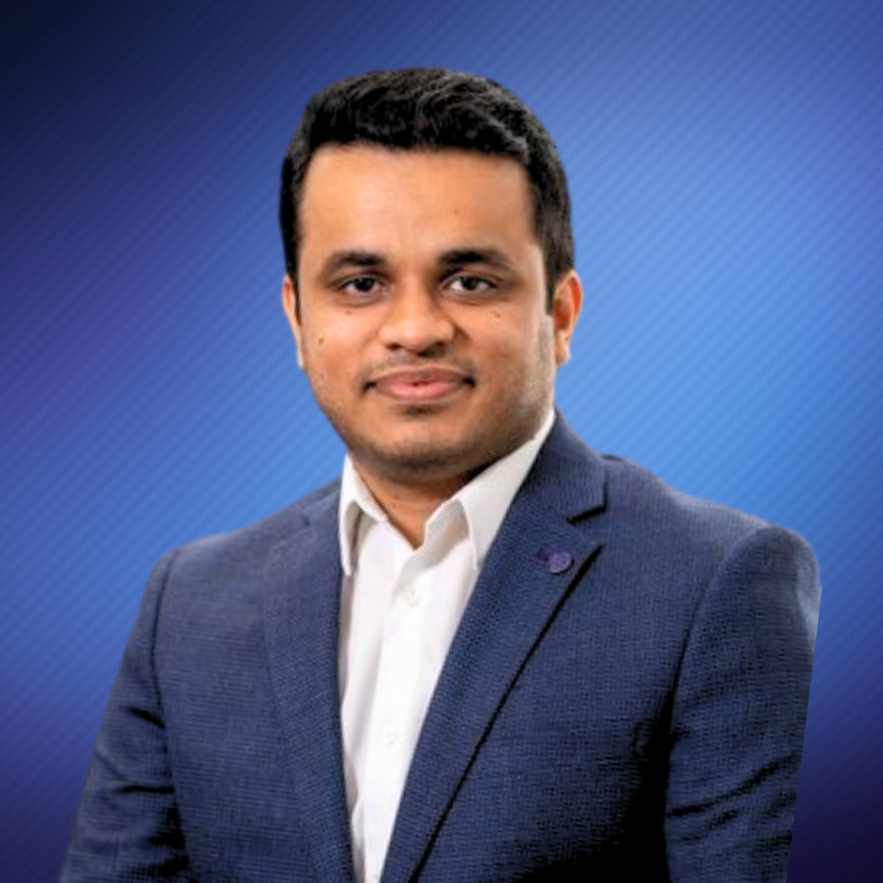 A professional man in a navy blue suit and white shirt posing against a blue background.