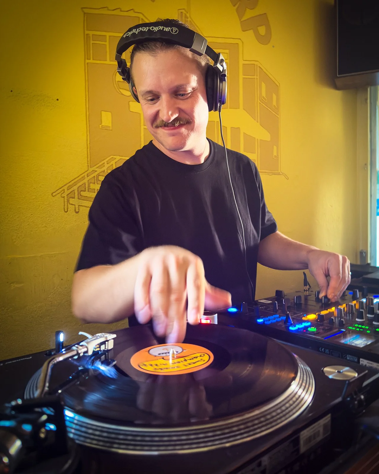 Photo of DJ Mack playing a DJ set at Amsterdam Vinyl Club. Amsterdam Vinyl Club organises community events for music lovers, record collectors and DJs.