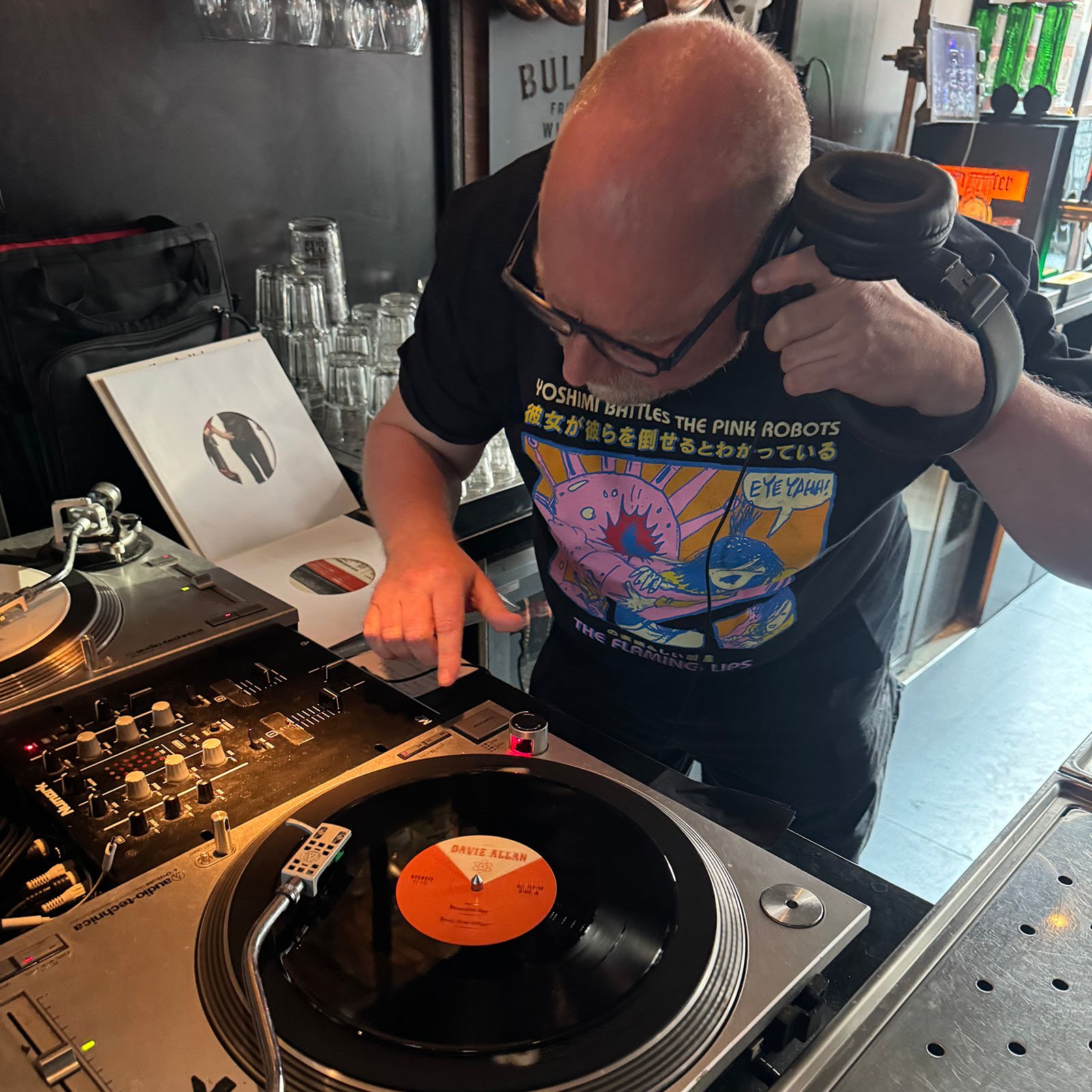 DJ Roland at the turntables playing a guest DJ set at Amsterdam Vinyl Club, a live music community event.
