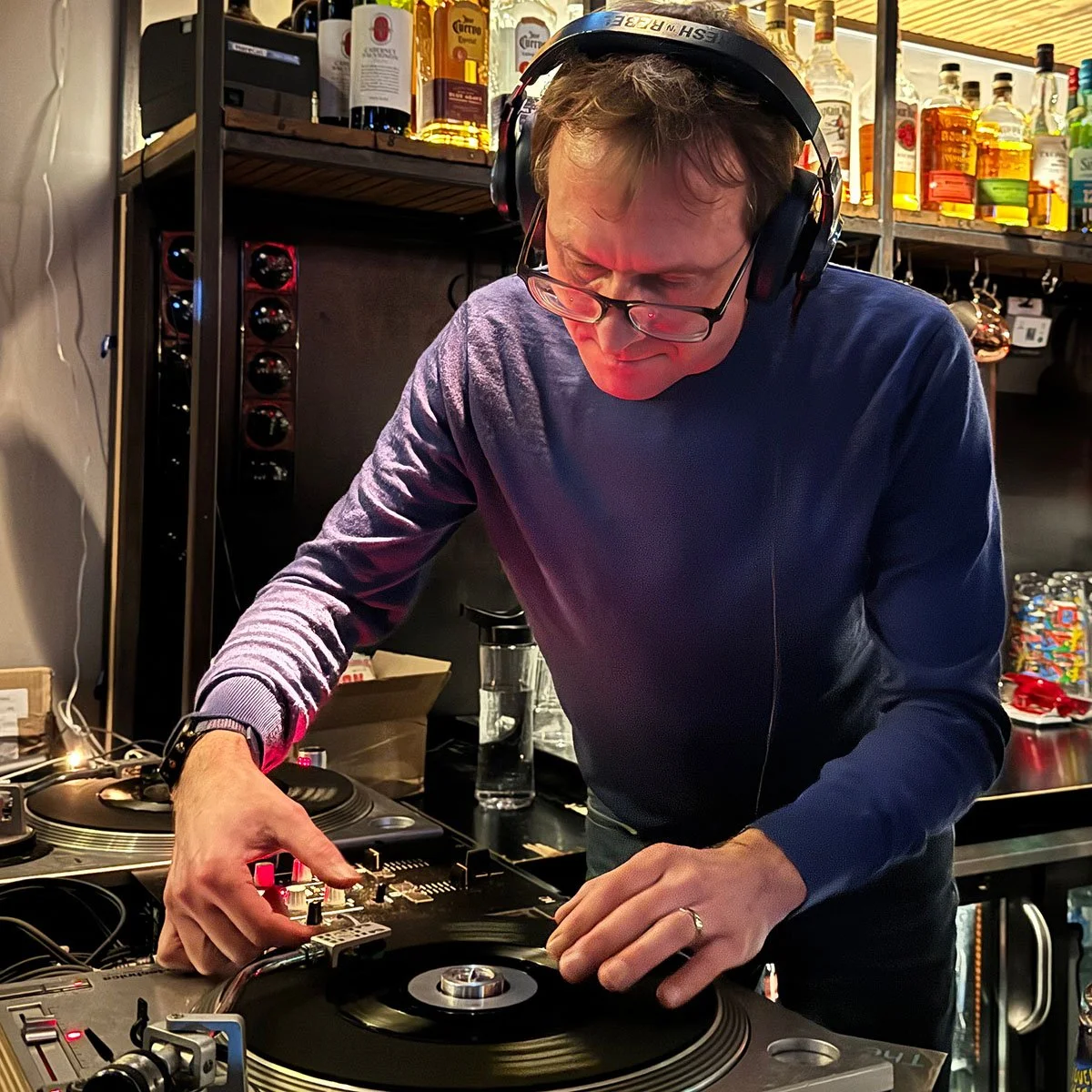 DJ Multimuck at the turntables playing a guest DJ set at Amsterdam Vinyl Club, a live music community event.