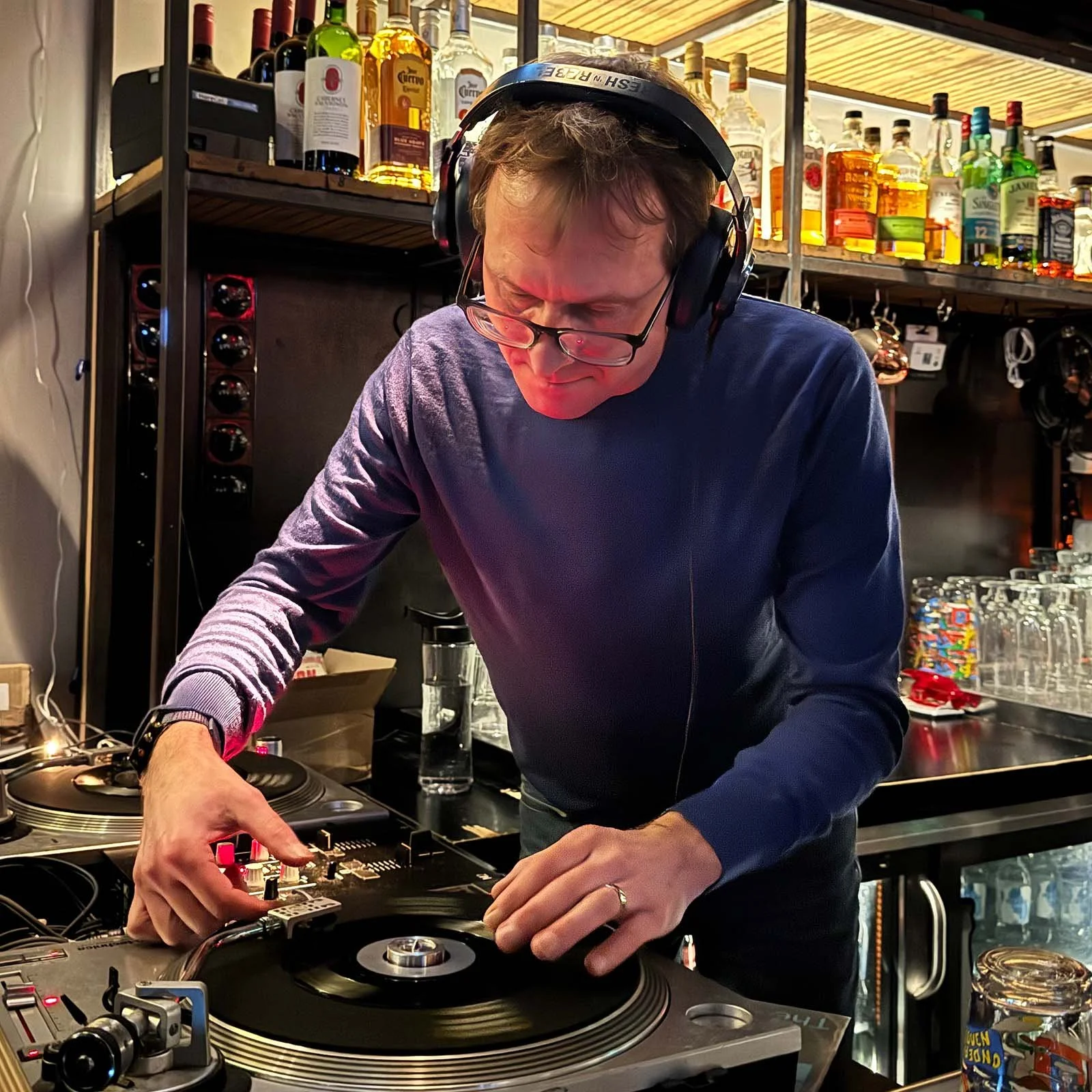 DJ Multimuck at the turntables playing a guest DJ set at Amsterdam Vinyl Club, a live music community event.