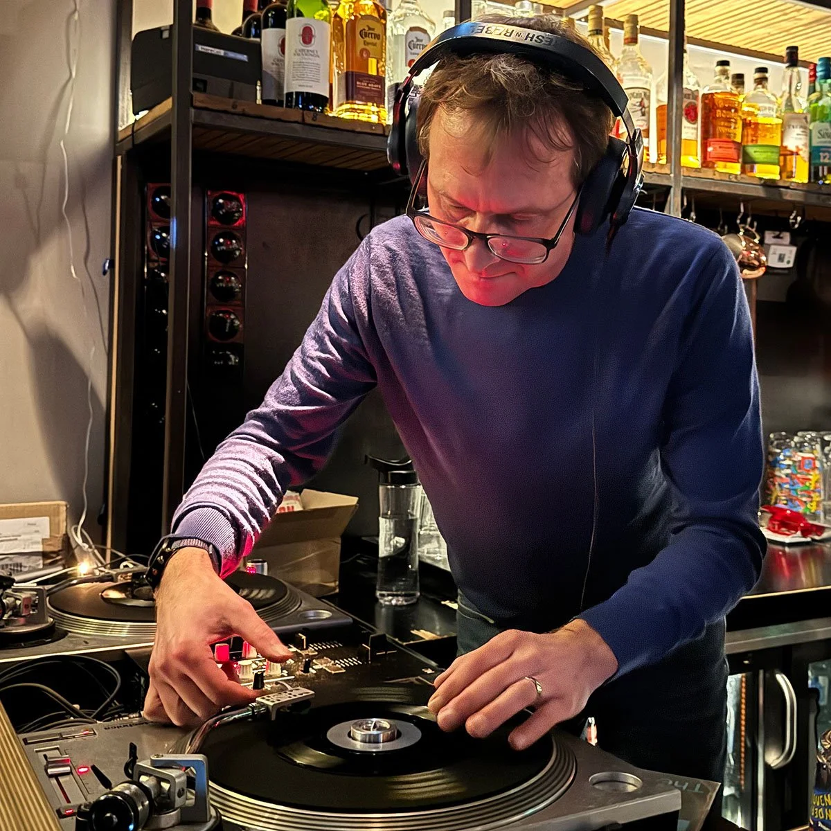 DJ Multimuck at the turntables playing a guest DJ set at Amsterdam Vinyl Club, a live music community event.