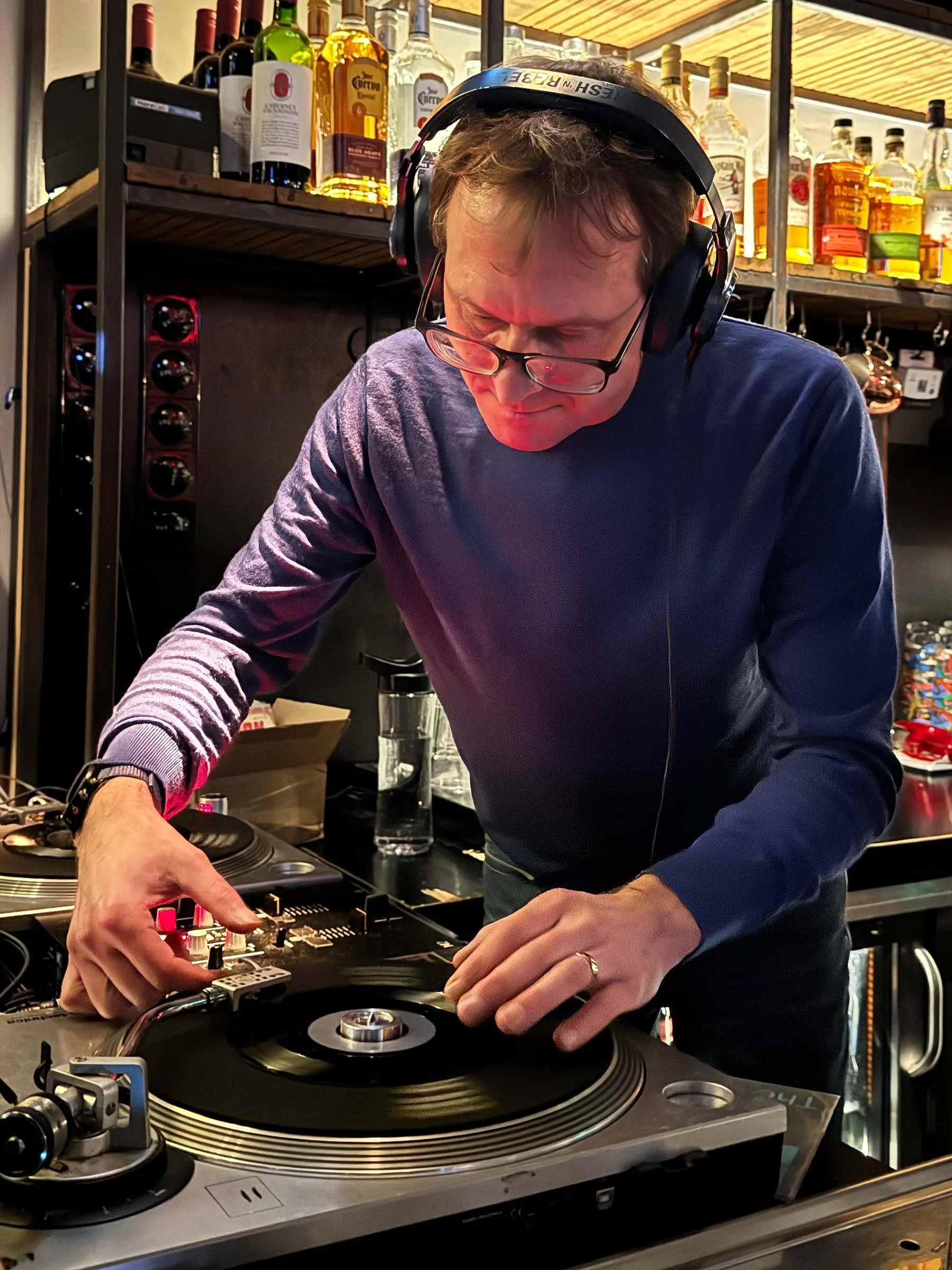DJ Multimuck at the turntables playing a guest DJ set at Amsterdam Vinyl Club, a live music community event.