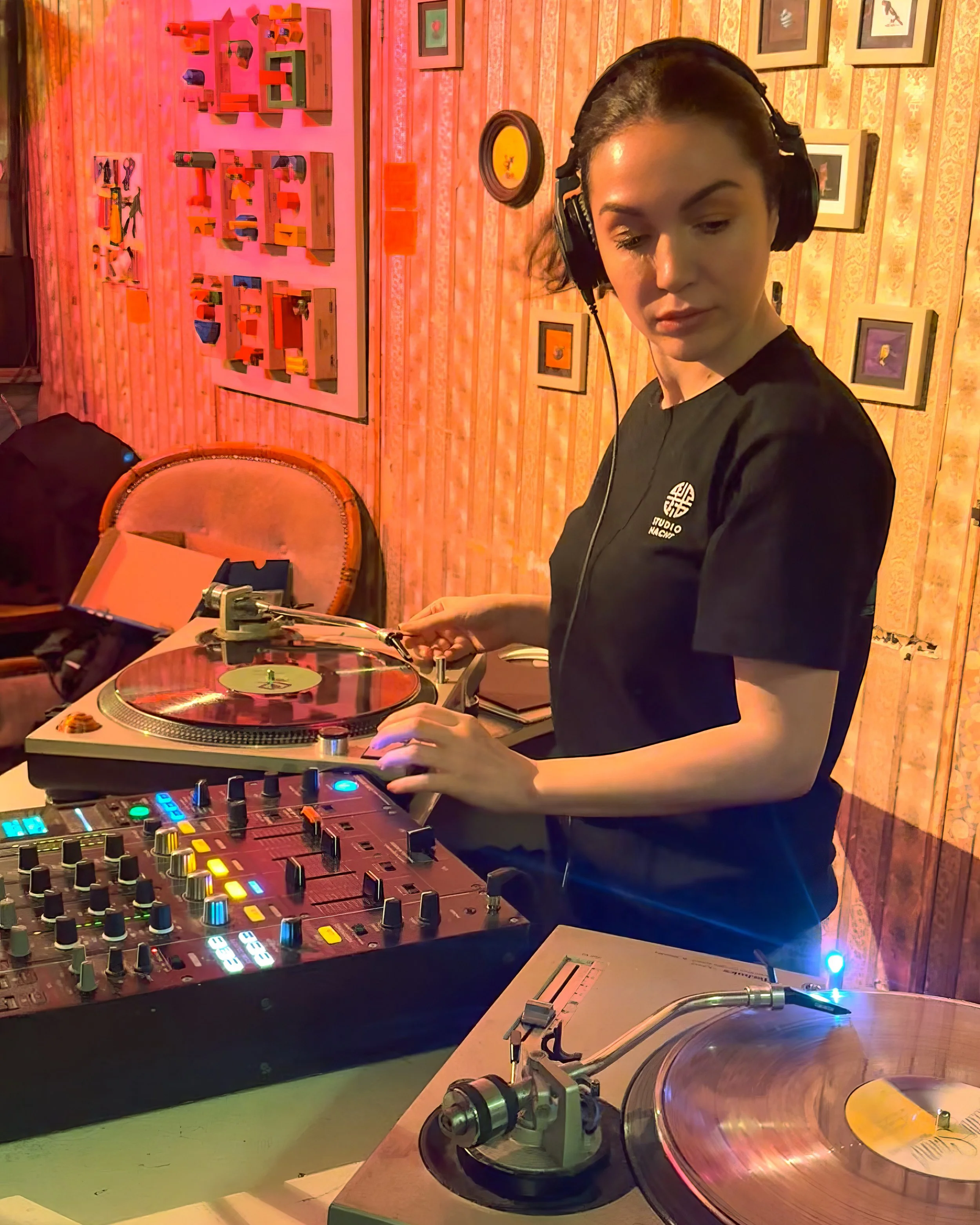 Sophia Sigma playing a guest DJ set at Amsterdam Vinyl Club. She's wearing headphones and a black T-shirt.