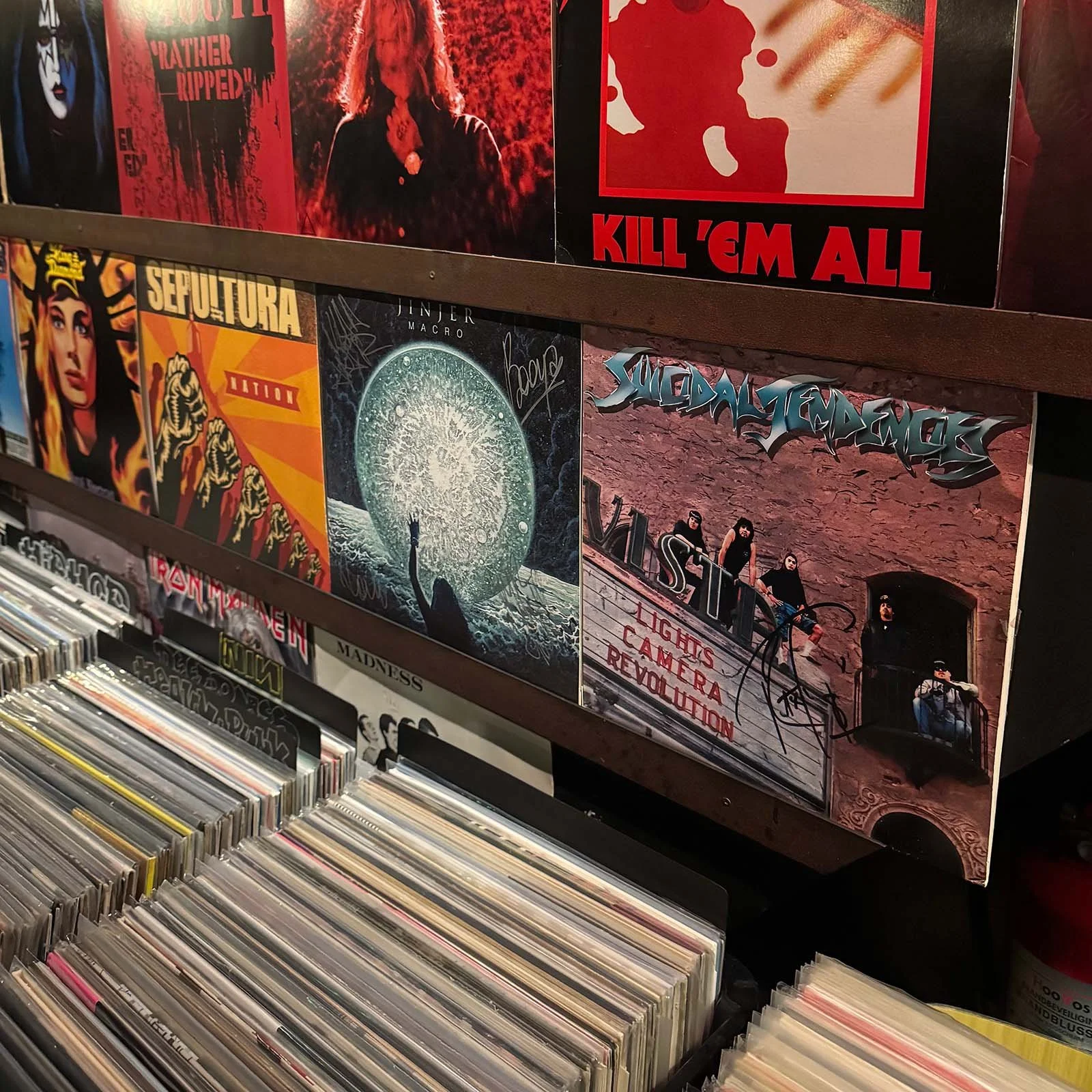 People shopping for vinyl records at an Amsterdam Vinyl Club live event, with records displayed on tables and artwork on the wall.
