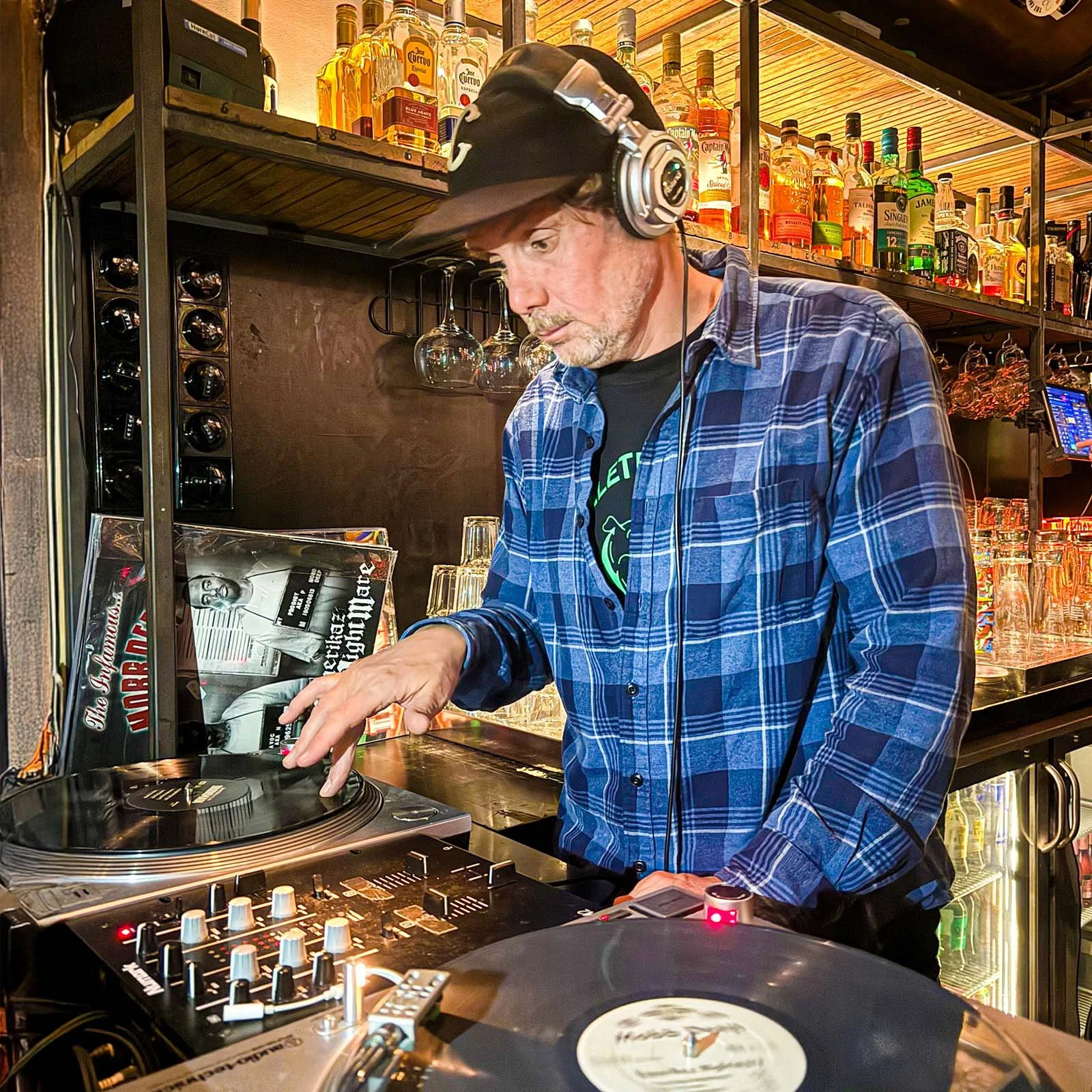 DJ Mouskovich at the turntables playing a guest DJ set at Amsterdam Vinyl Club, a live music community event.
