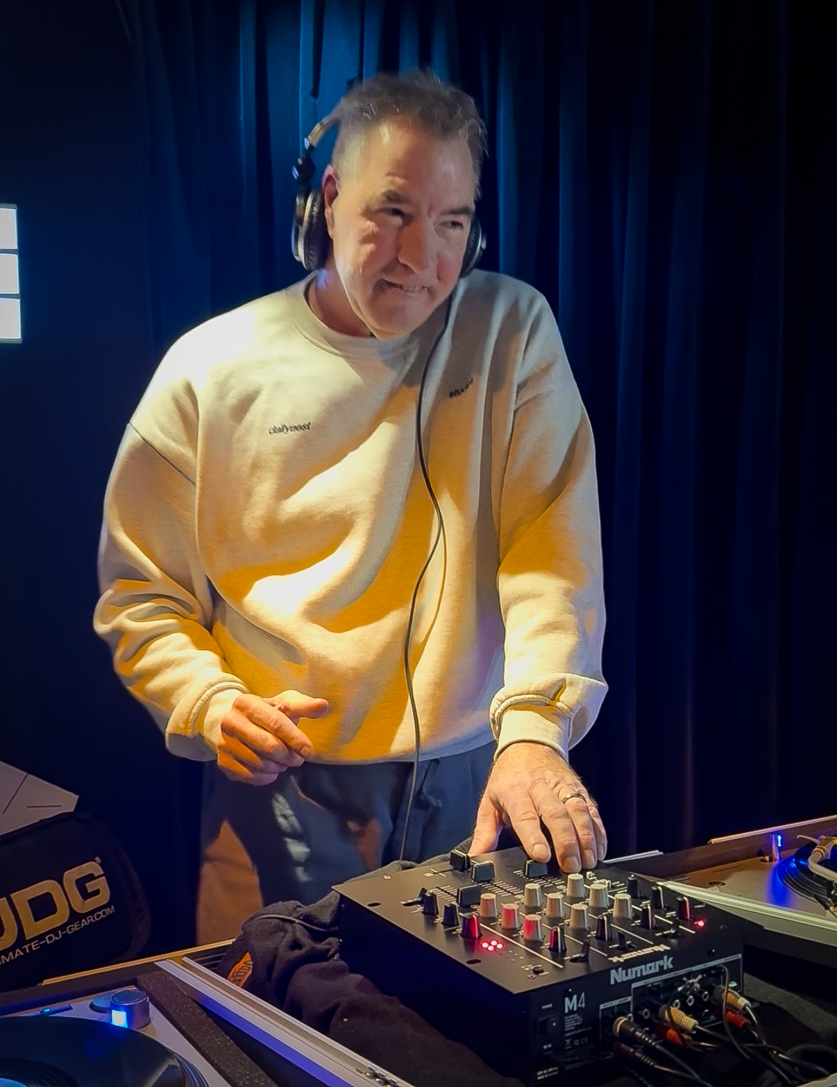 DJ Jaimy playing a guest DJ set at Amsterdam Vinyl Club. He's wearing headphones and a white sweatshirt