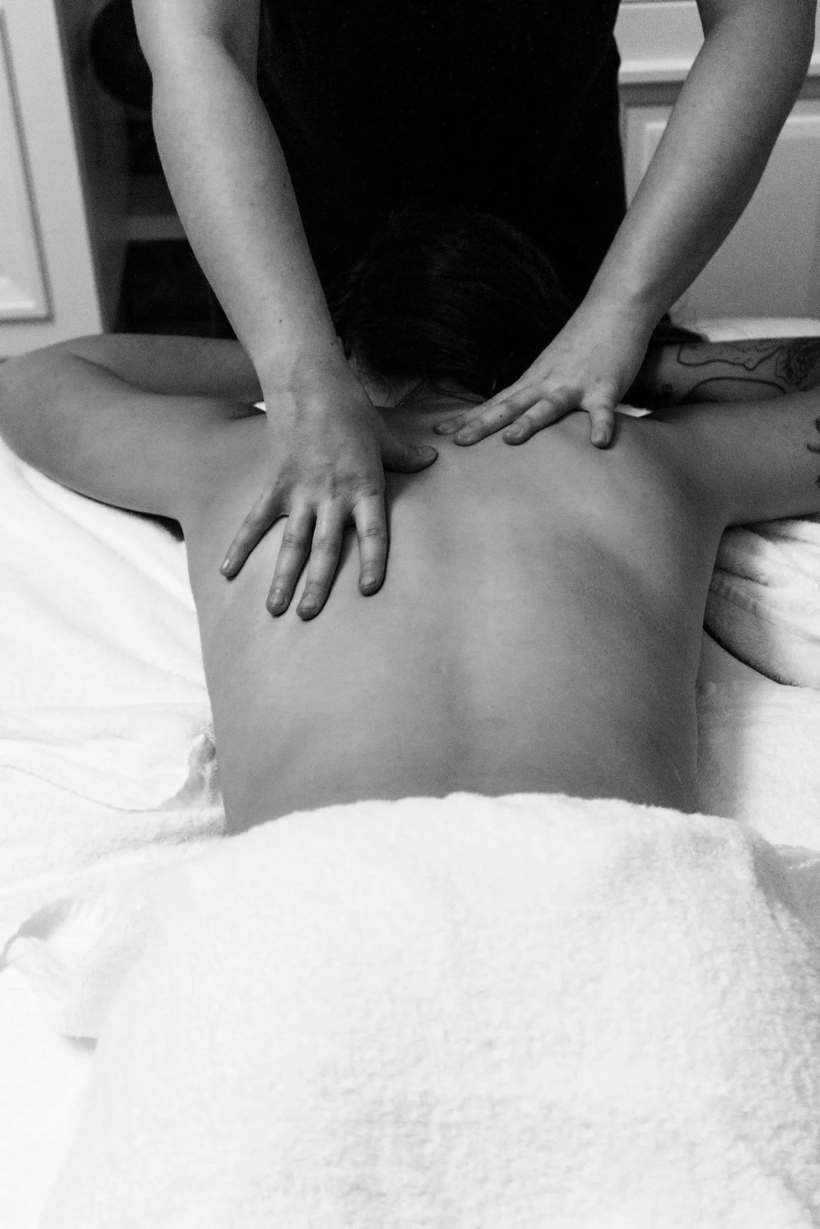 A person receiving a back massage from a massage therapist in a therapy room.