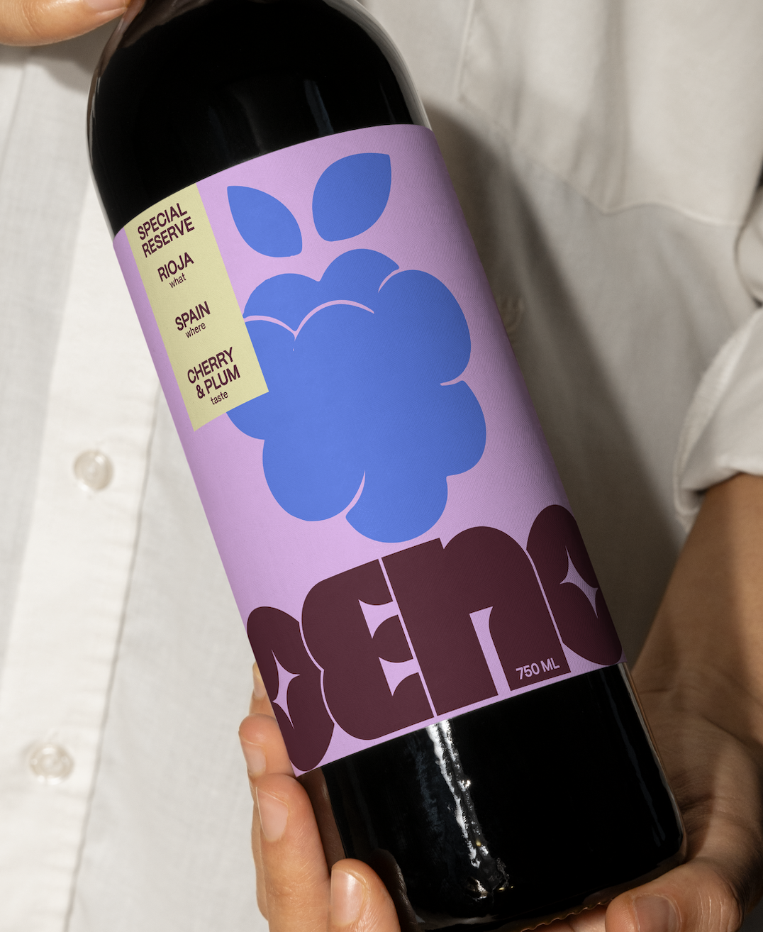 A person holding a bottle of wine with a purple label that features a blue cluster of grapes and the brand name 'CEROS'.