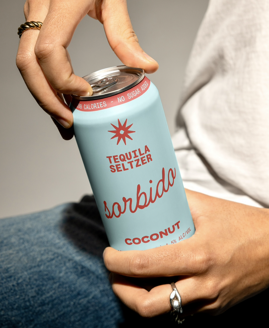Person holding a can of Sorbido coconut tequila seltzer, with their thumb and fingers gripping the top and bottom of the can.