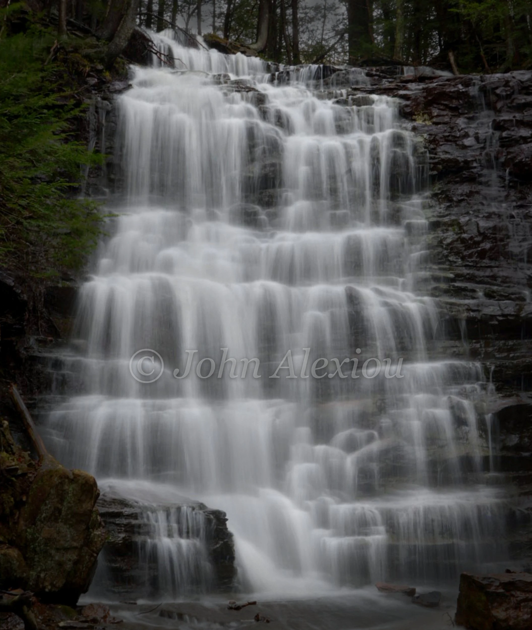 01 · One Ledge at a Time
White water spreads across a staircase of dark rock beneath the trees.
© John Alexiou · 2026 · Northeast Pennsylvania