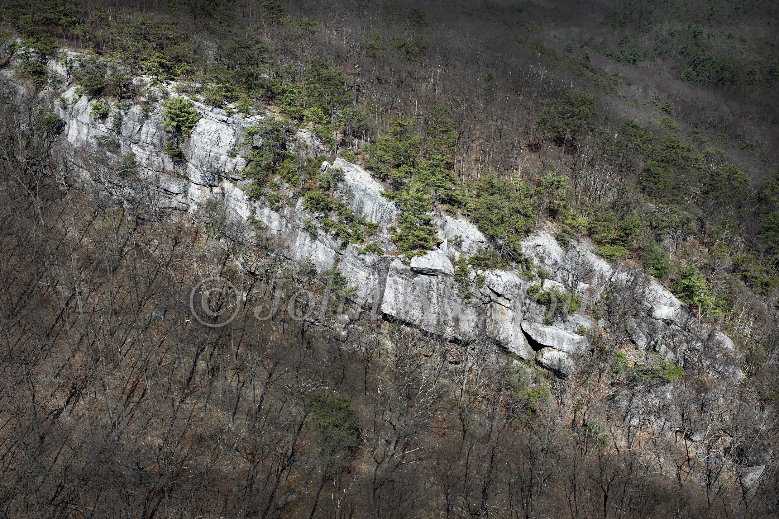 11 · Pale Stone: A long pale rock face stretches through trees across the hillside.

© John Alexiou · 2025 · Mocanaqua