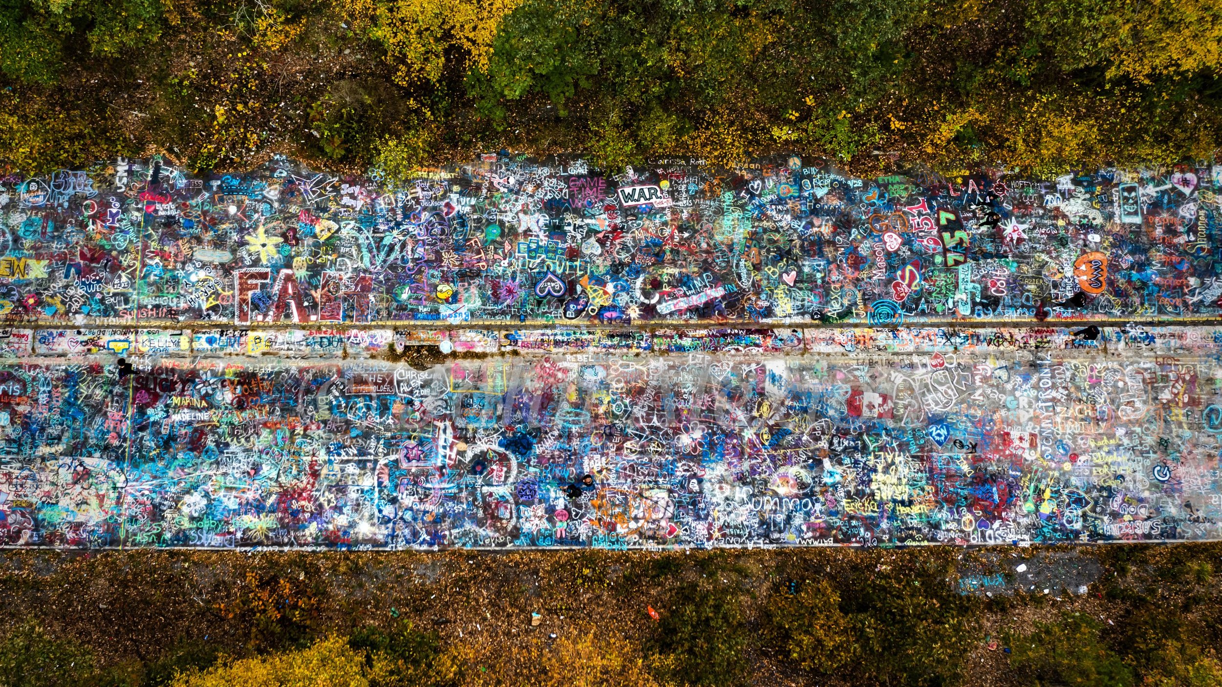 05 · Layers of Memory: Painted pavement fills an overhead composition between autumn trees at Graffiti Highway, Centralia, Pennsylvania, 2019.

© John Alexiou · 2019 · Centralia