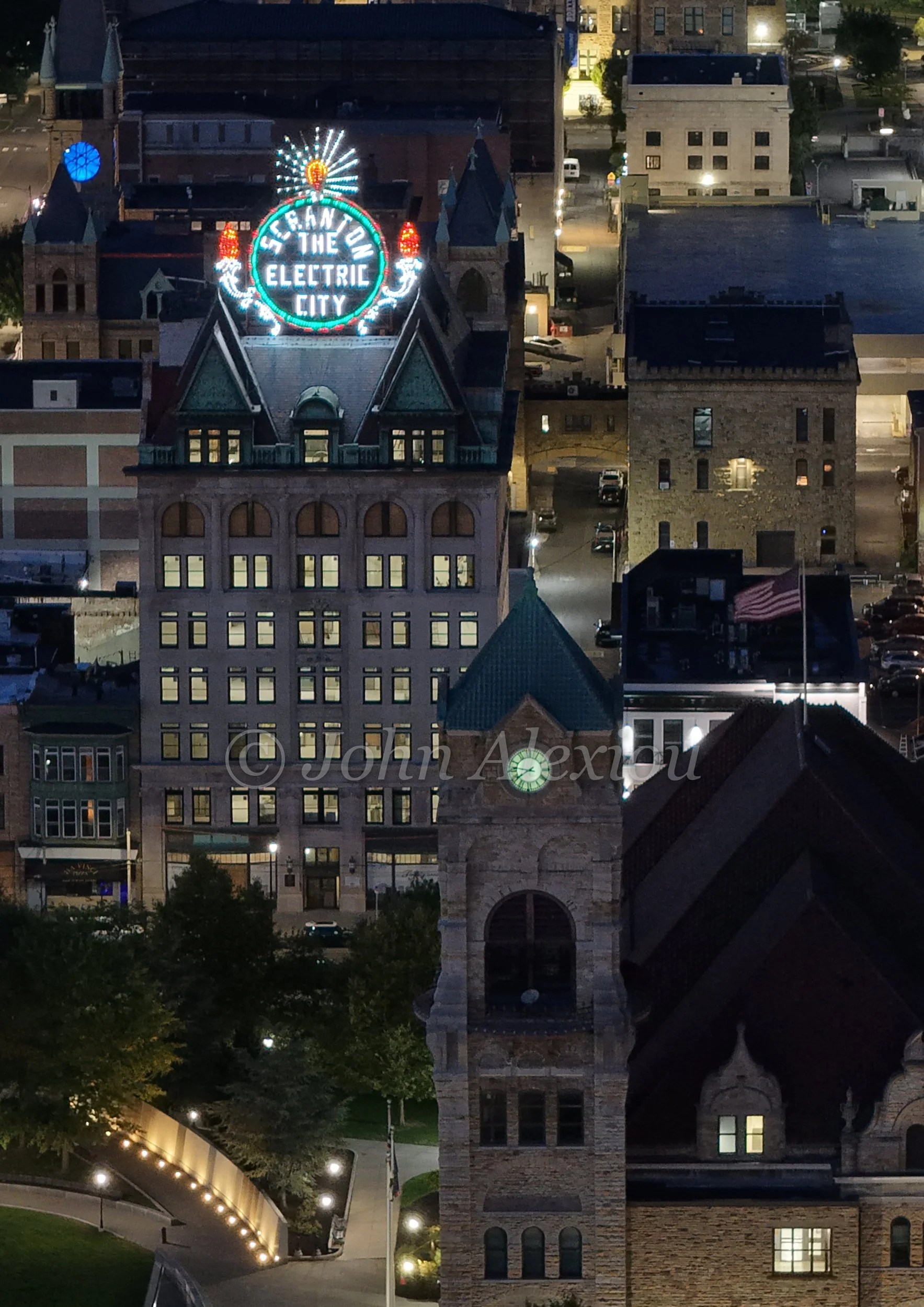 03 · Above the Evening Streets
The illuminated sign rises above downtown Scranton, with lit windows and streets stretching beyond it.
© John Alexiou · 2025 · Electric City, Scranton