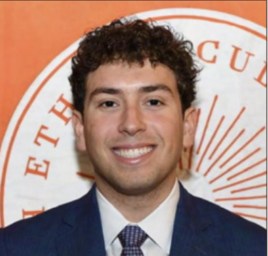 A young man with dark curly hair wearing a blue suit, white shirt, and patterned tie, smiling in front of an orange background with a circular logo.