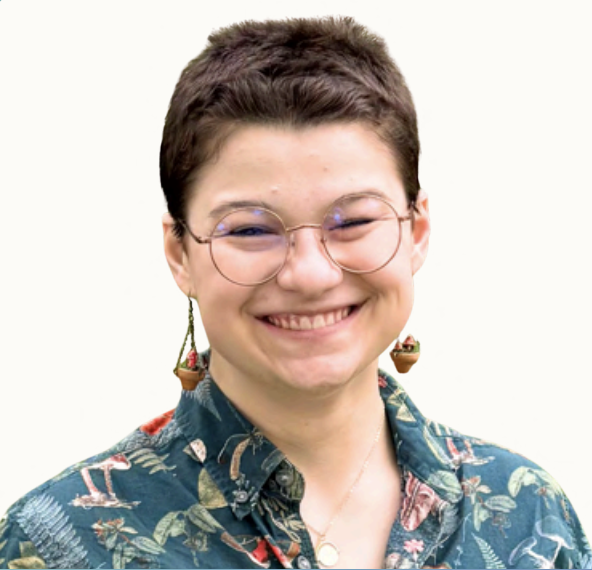 Smiling person with short brown hair, glasses, and colorful earrings, wearing a tropical patterned shirt.