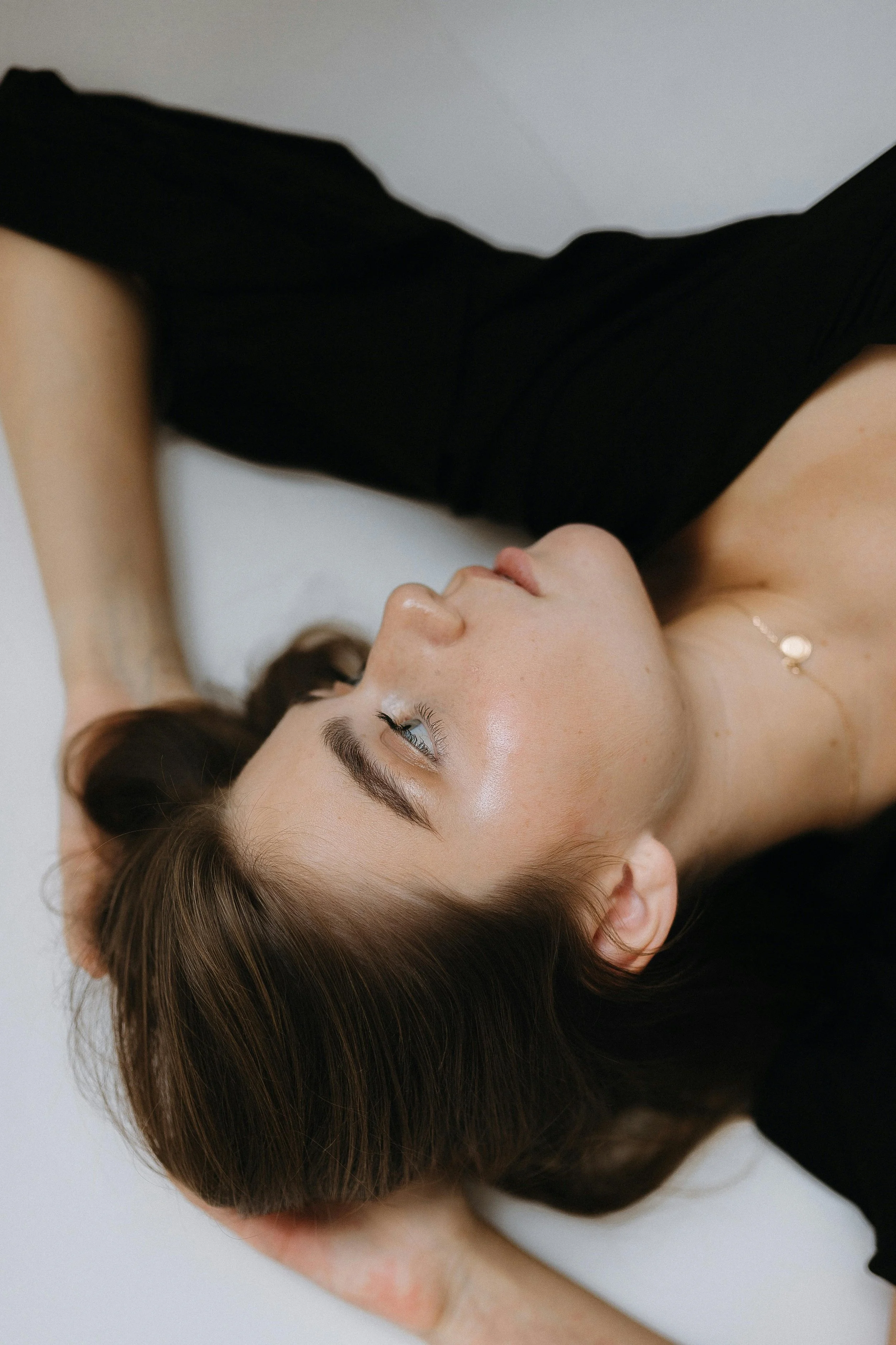A woman with long brown hair lying down, resting her head on a person's hand.