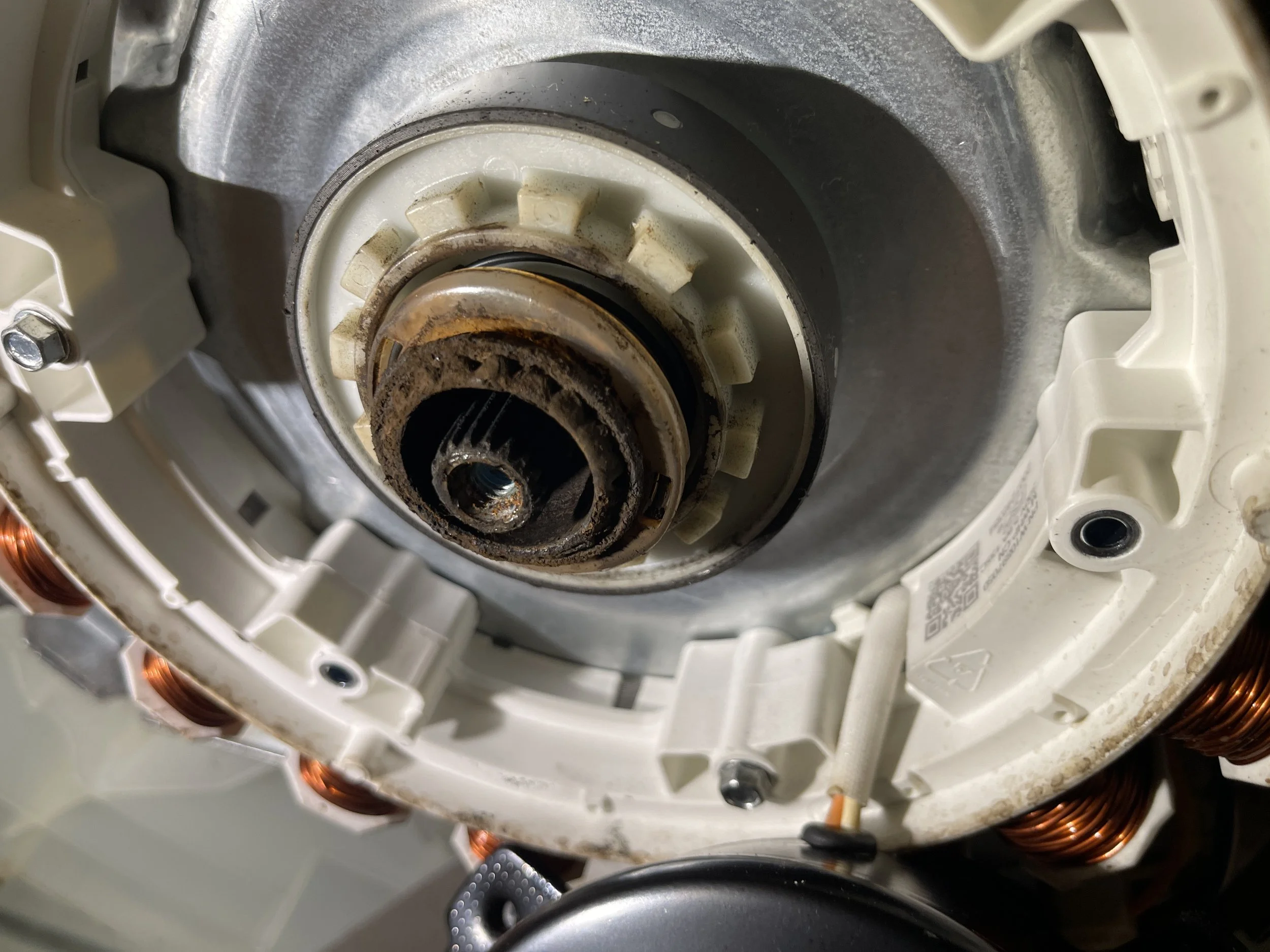 Close-up of the internal rotor and stator components of an electric motor, showing rusted and clean metal parts.