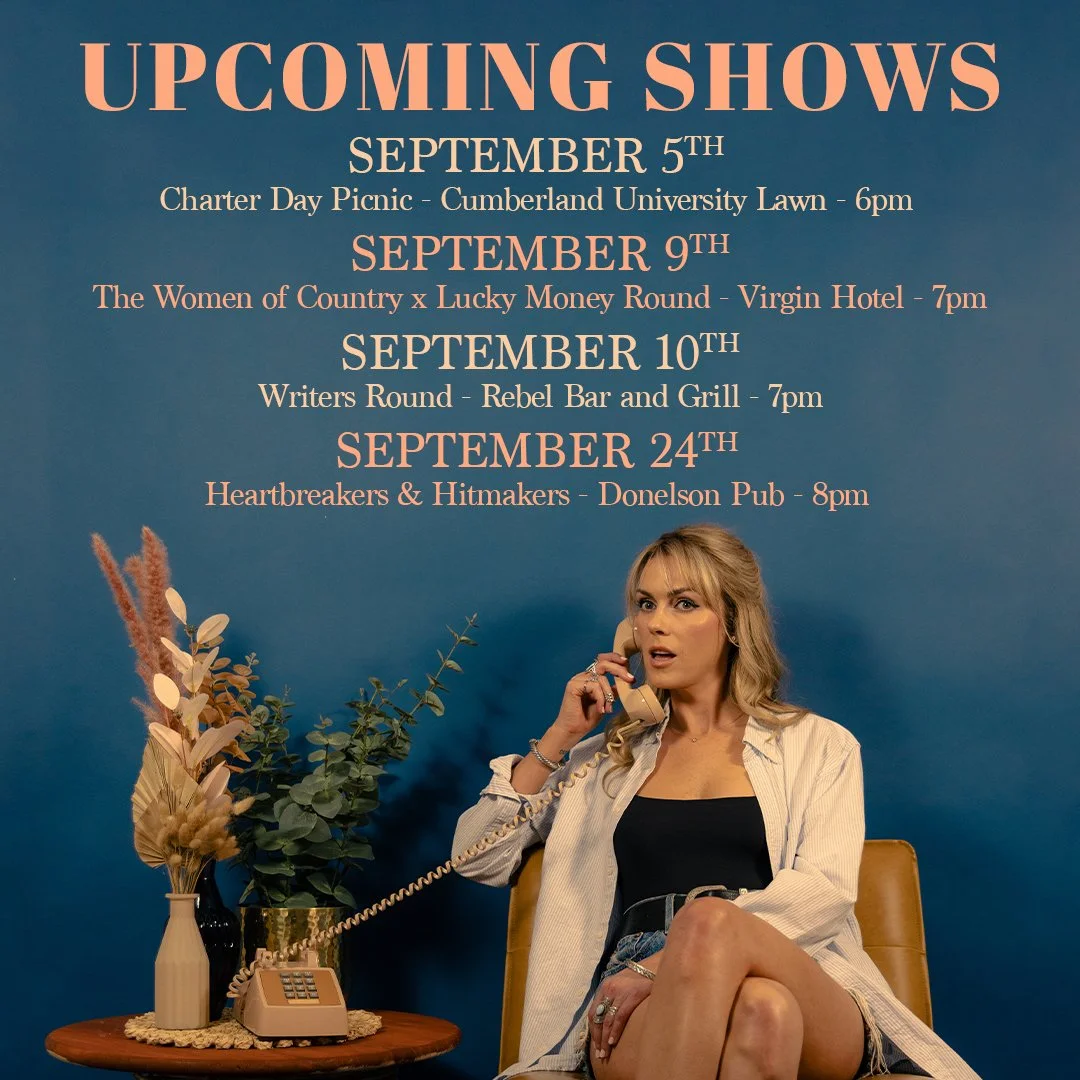Noelle Toland is on the phone in front of a blue wall with her tour dates graphically written out above her head.