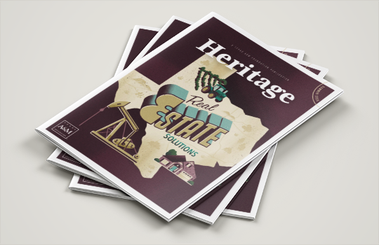 Three magazine copies are stacked on a tan surface. The top cover features an illustration of the state of Texas and "Real Estate Solutions."