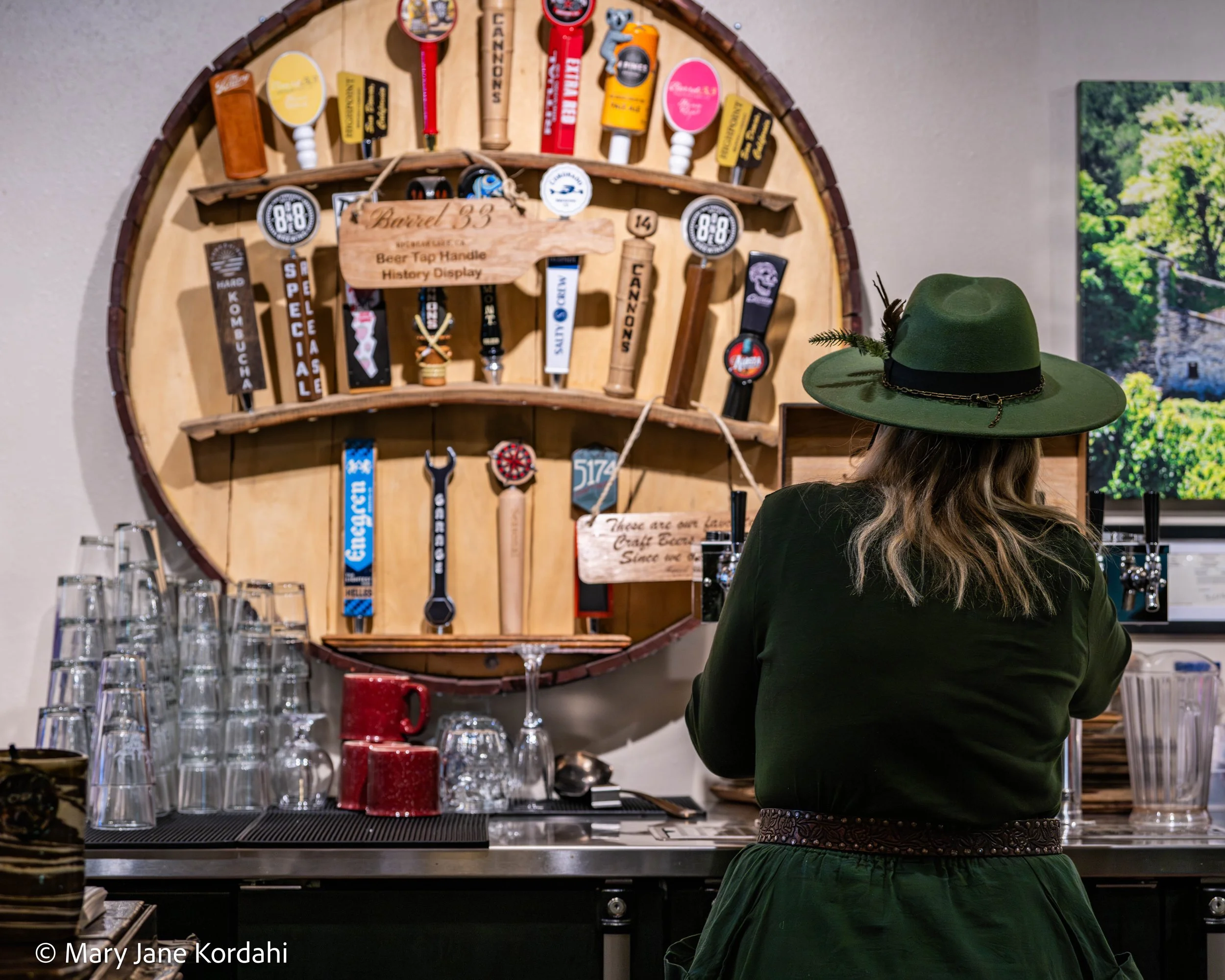 A tap handle wall behind a bartender pouring beer.
