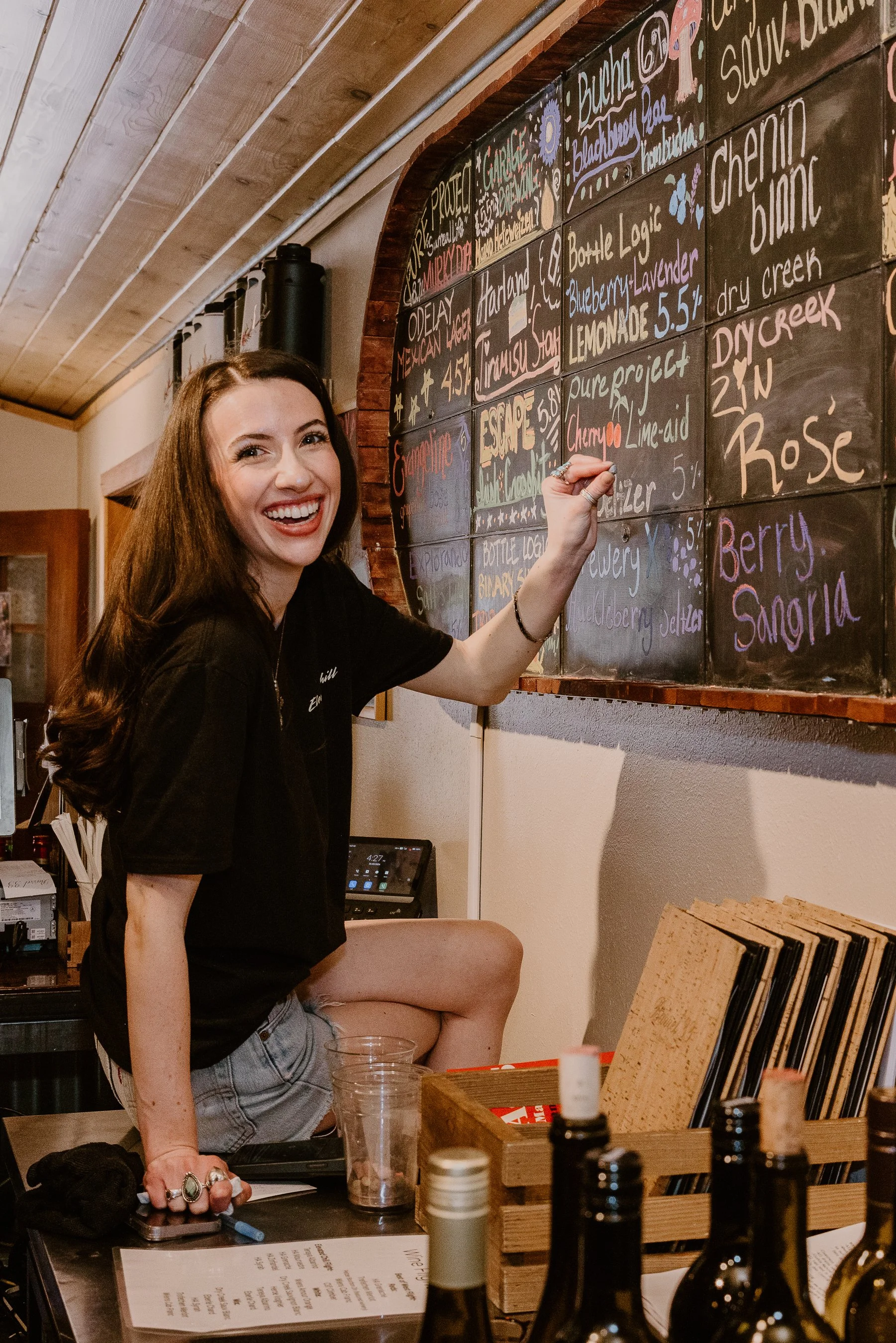 gal writing on the tap chalkboard