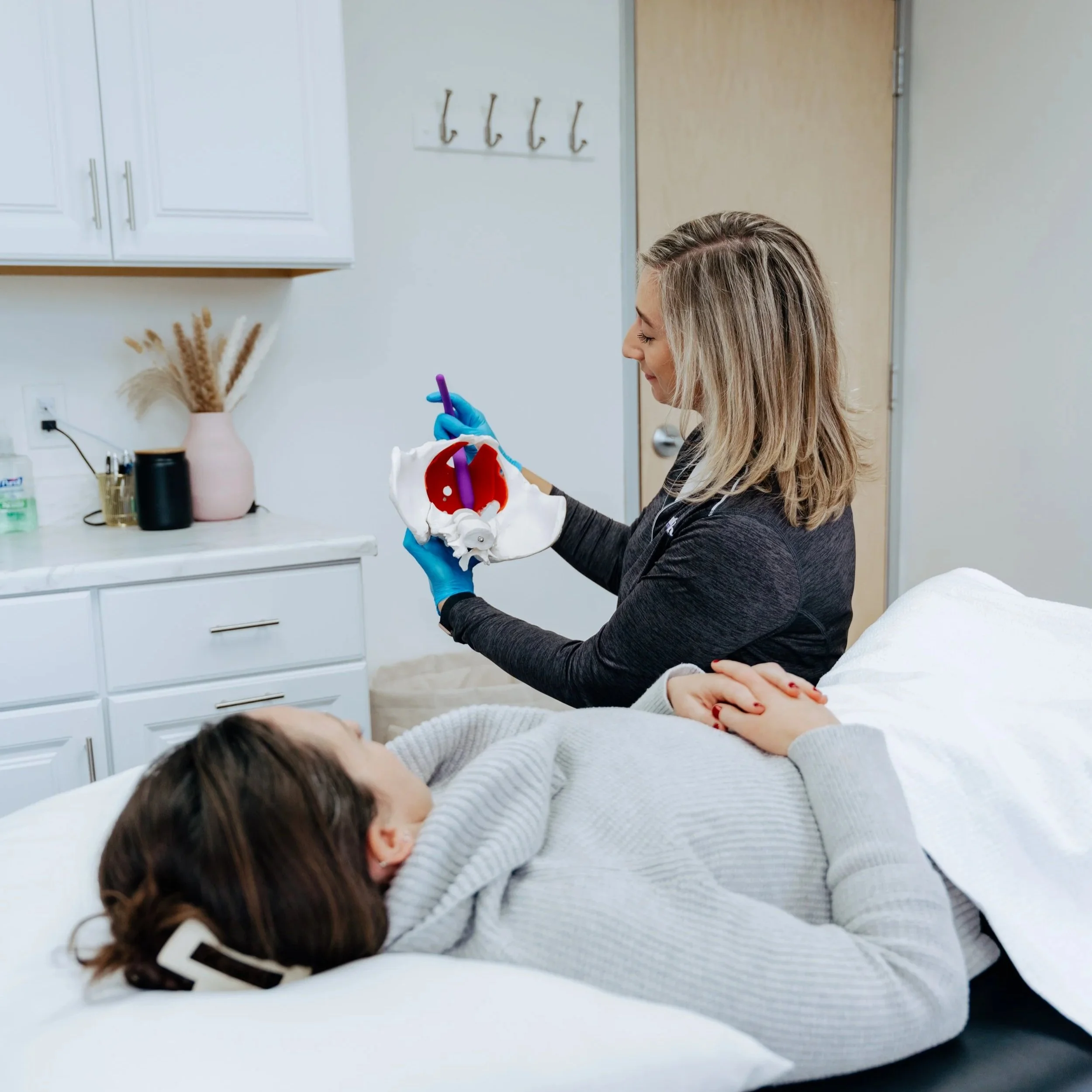 Jill Burkhard, PT, using a pelvic model to explain pelvic floor anatomy at Triumph Physical Therapy in Denver.