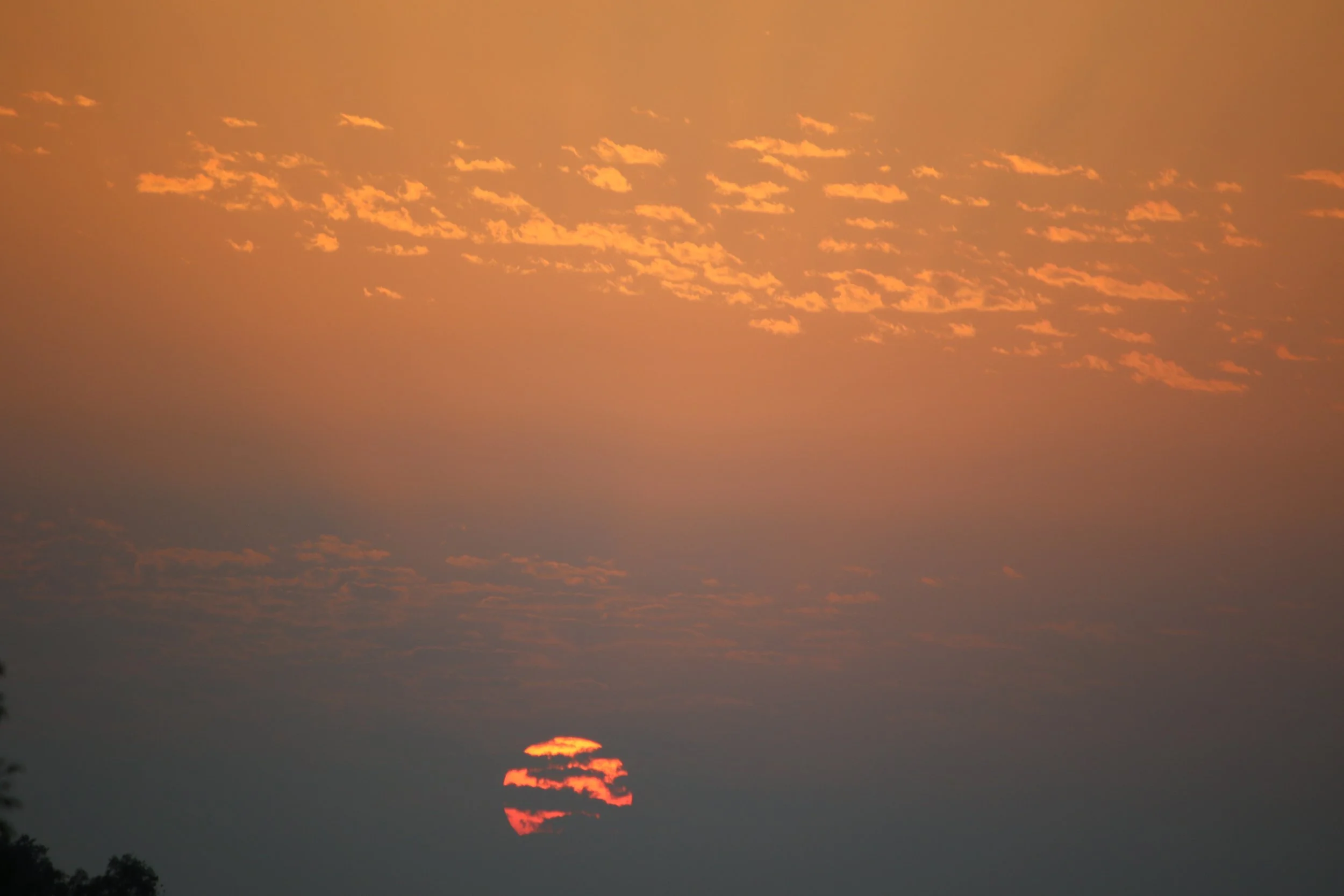 Coucher de soleil avec un ciel orange et des nuages.