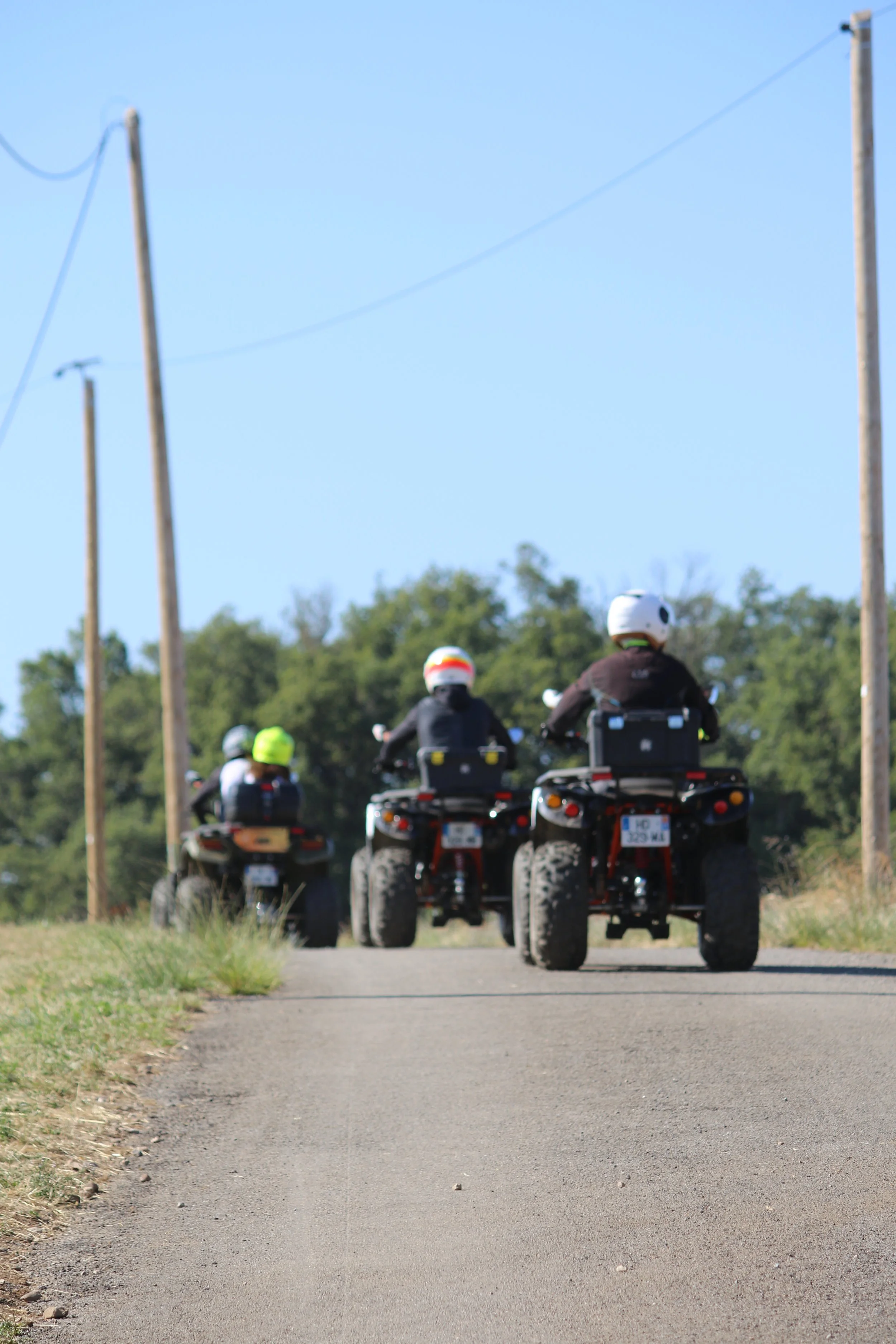 Groupe de personnes faisant de la moto tout-terrain sur une route rurale, portant des casques de protection.