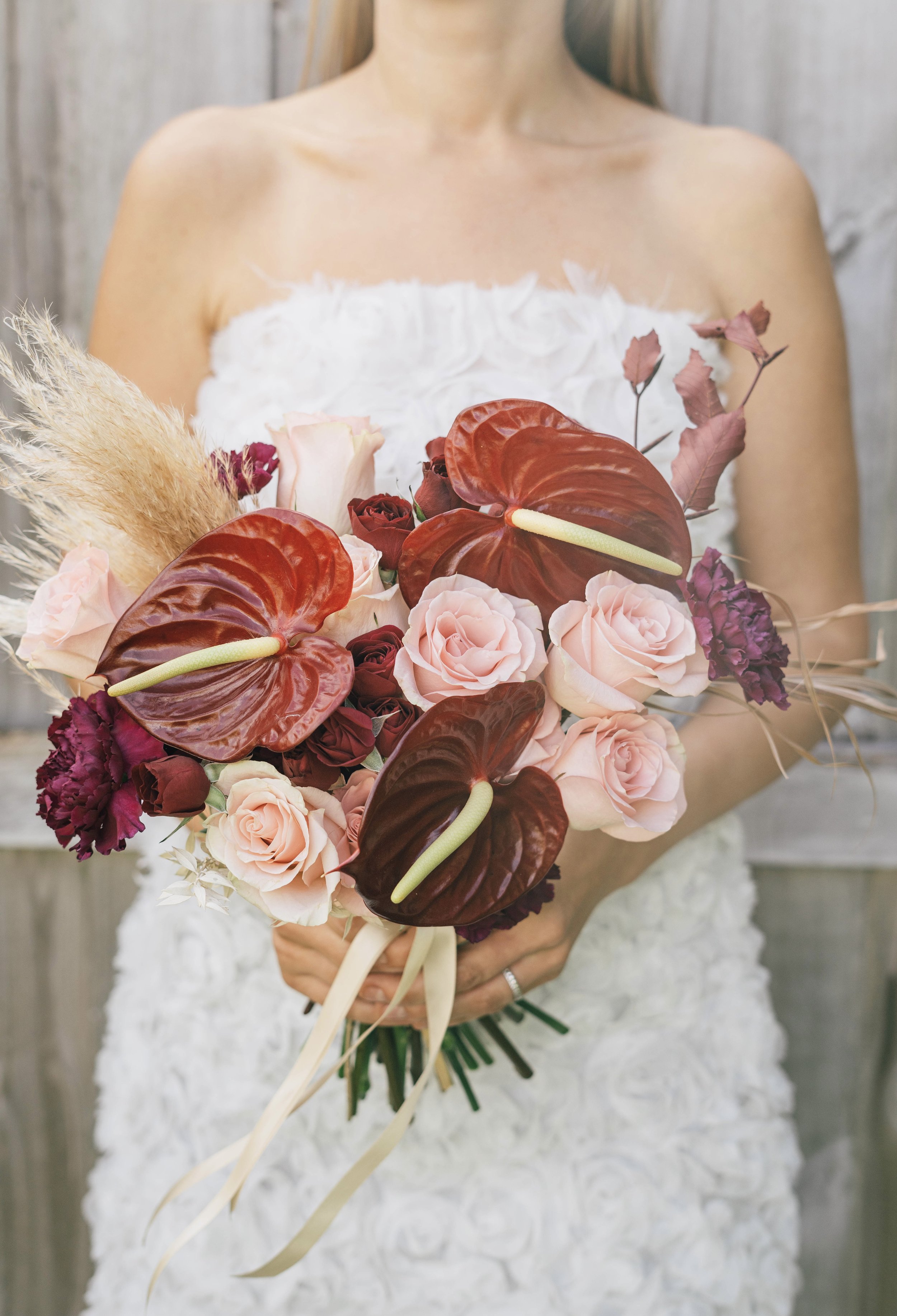  bride holding burgundy anthurium and pink rose wedding bouquet 