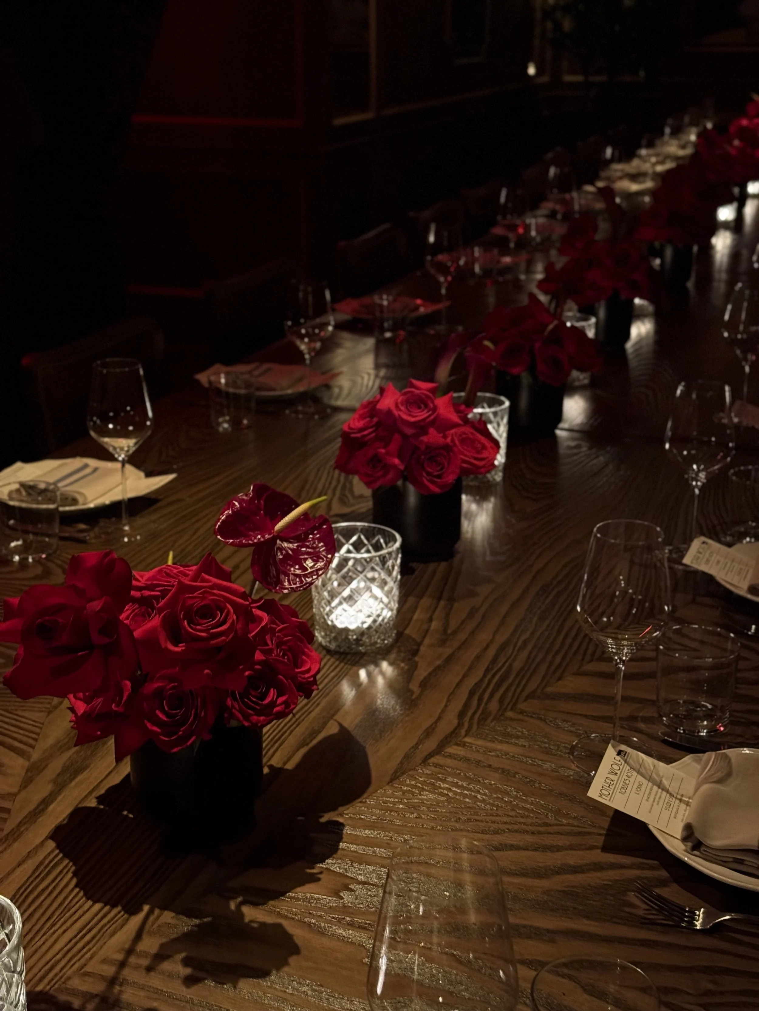  burgundy rose centerpieces along a candlelit reception table 