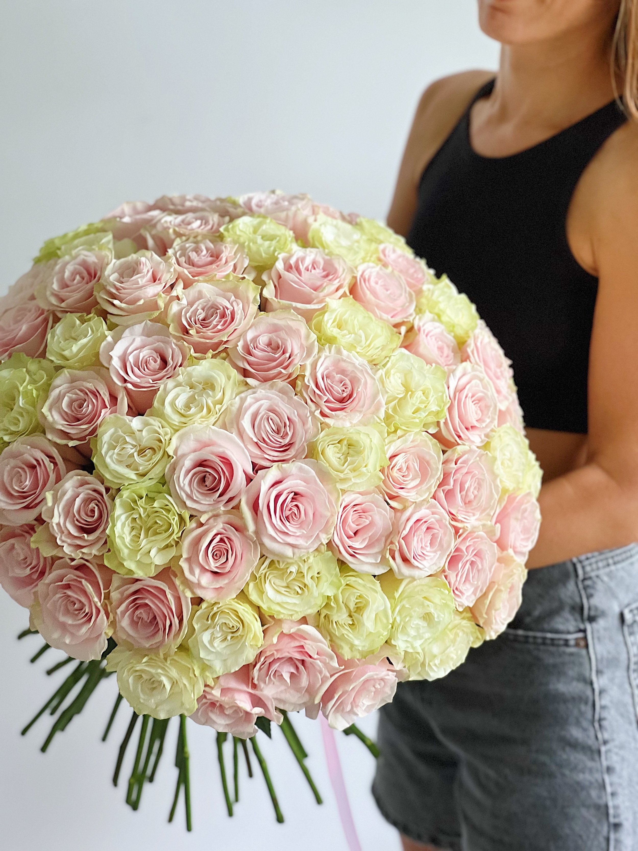 A woman holding a large bouquet of pink and white roses.