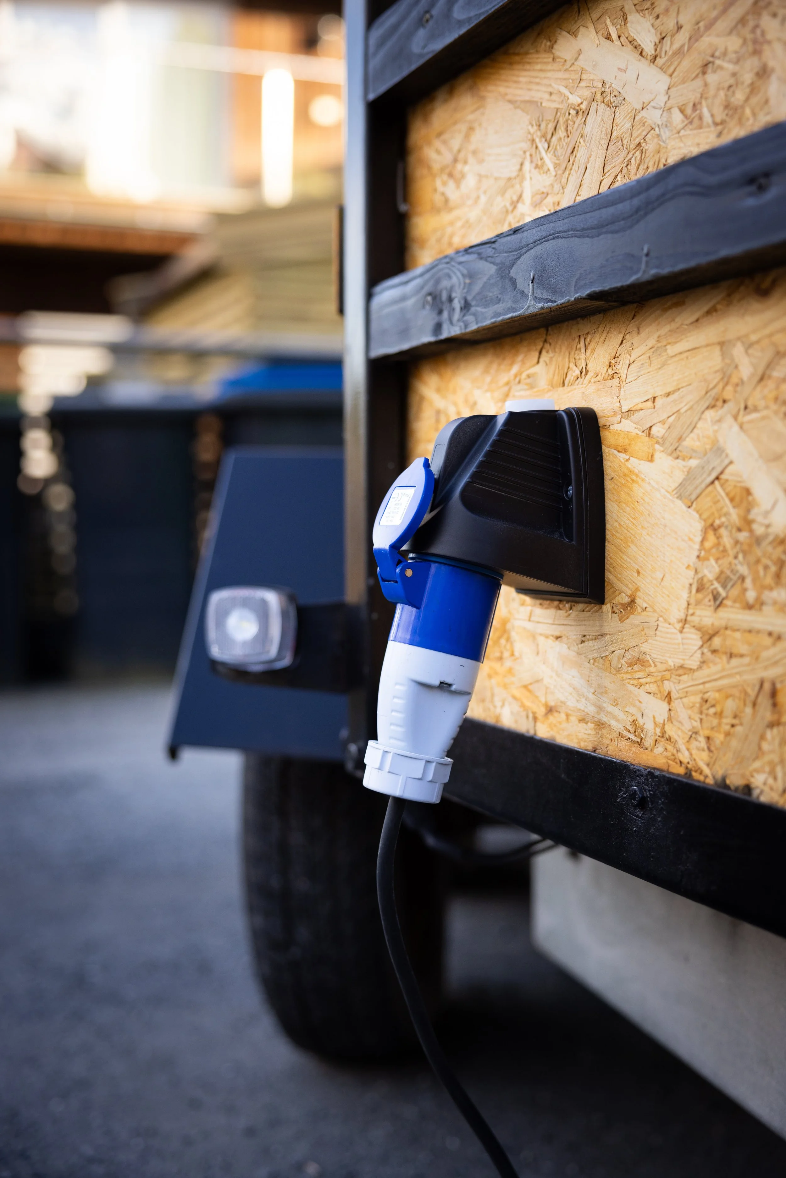 Close-up of an electrical power plug connected to a wooden surface with an electrical outlet on a mobile construction or work site.