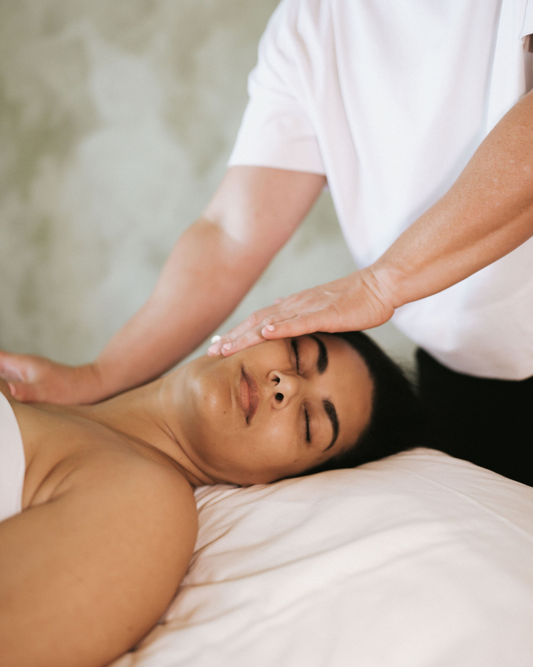 Hands resting gently against a client's jaw and cheek during a calming facial massage at FaceUp Studio