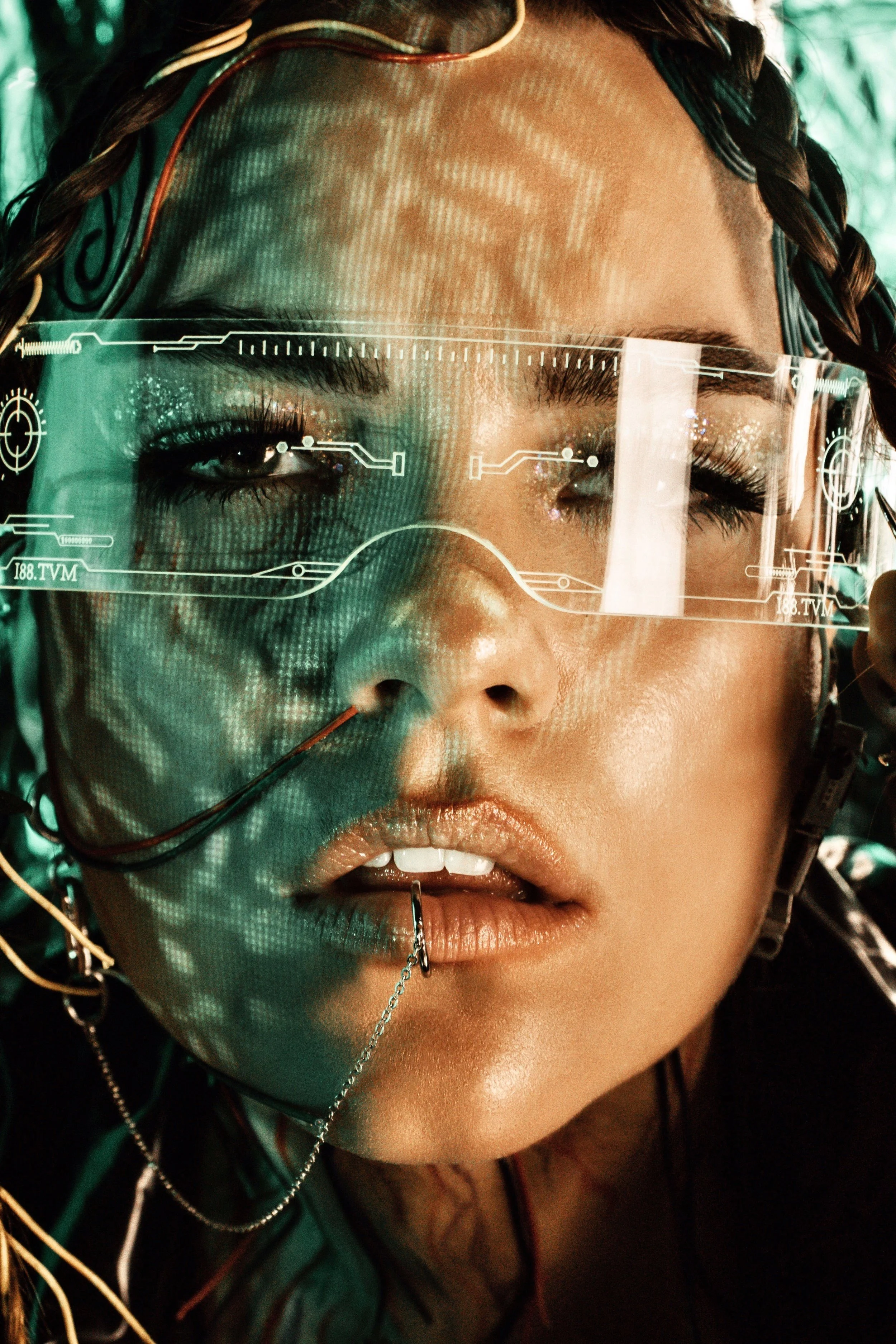 A close-up of a woman with cyberpunk-style accessories, wearing virtual reality glasses with holographic displays. She has braided hair, metallic makeup, and facial piercings. This is a photo of the founder of No Labels Studio, Maddi Krulicki.