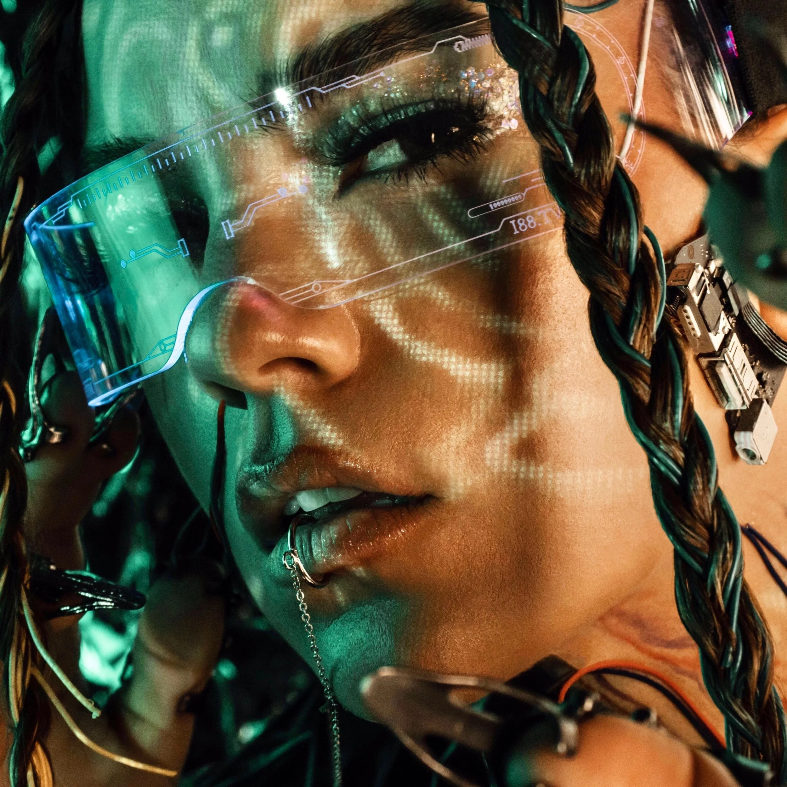 Close-up of a woman with elaborate hairstyle wearing a futuristic visor, surrounded by electronic components and wires, with digital holographic displays projecting around her face. This is a photo of the founder of No Labels Studio, Maddi Krulicki.