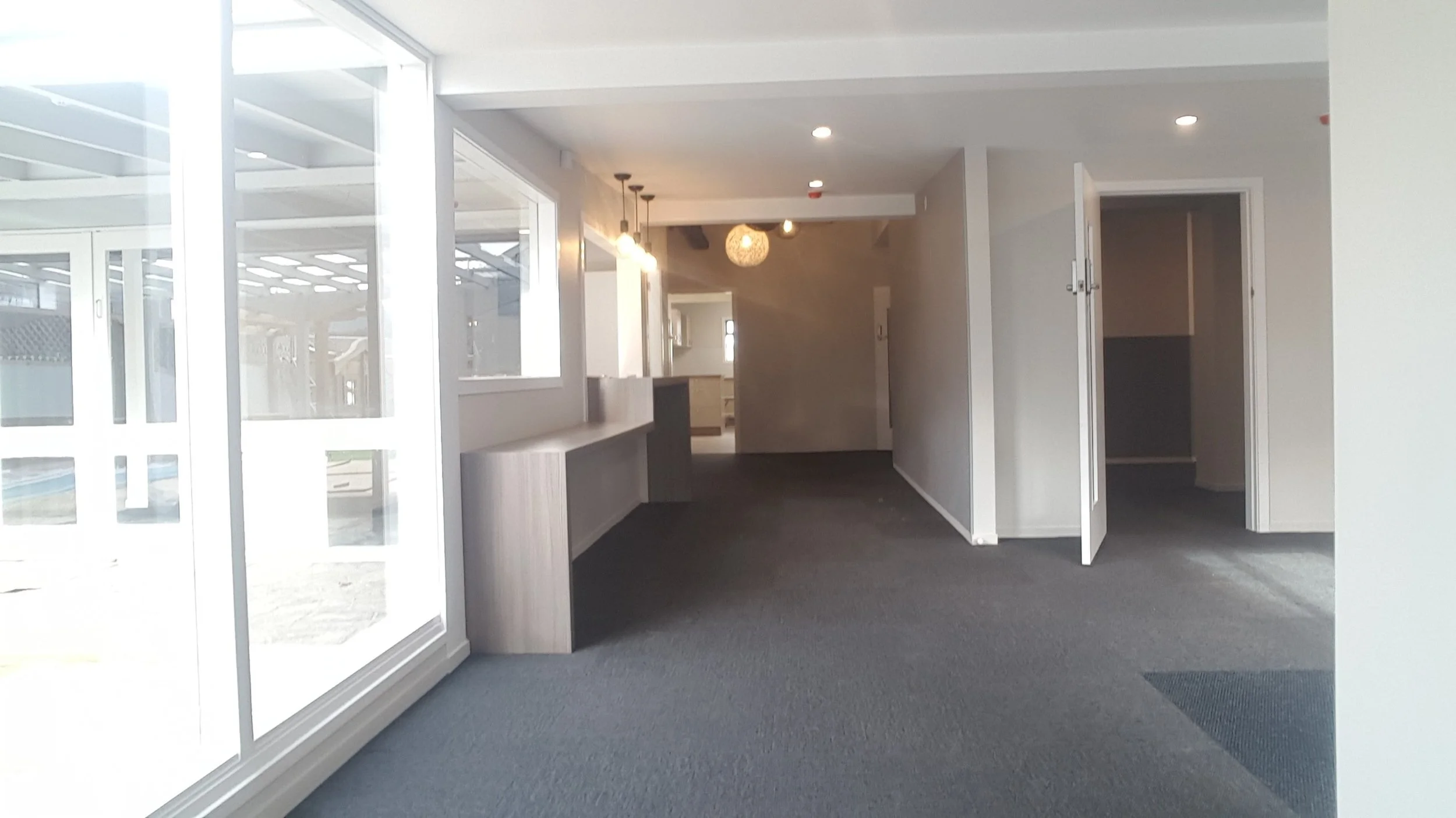 Empty room with large glass sliding doors, gray carpet, and open closet with double doors.