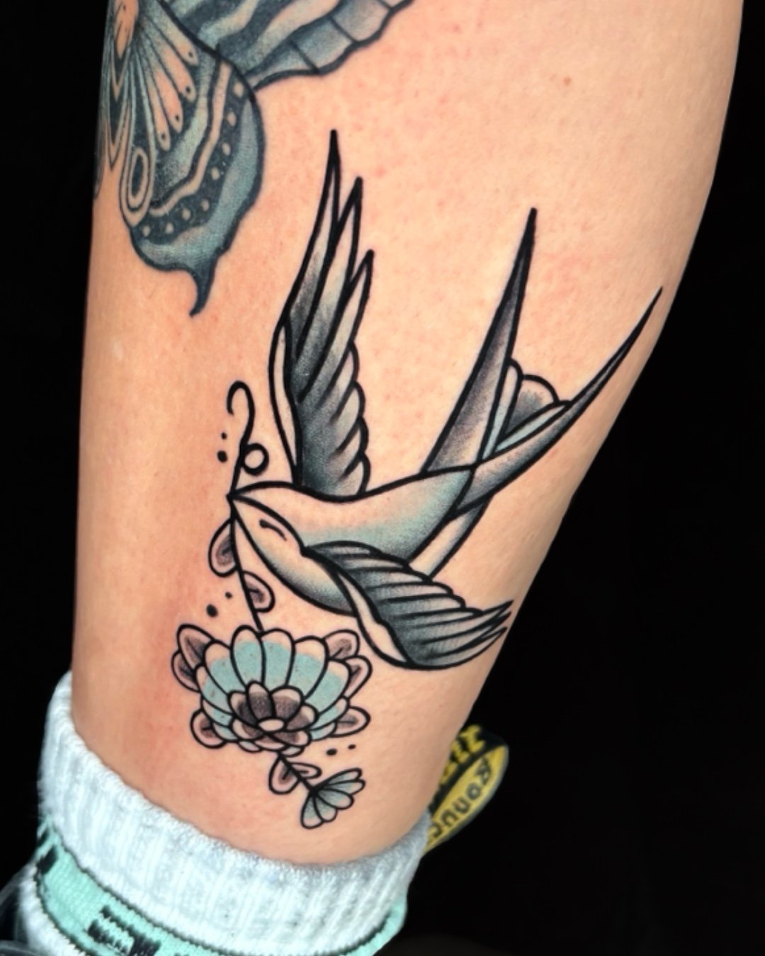 American Traditional swallow tattoo in West Palm Beach, Florida, created with bold black linework and classic shading. The swallow is one of the most iconic symbols in traditional tattooing, representing loyalty, freedom, safe return, and new beginni